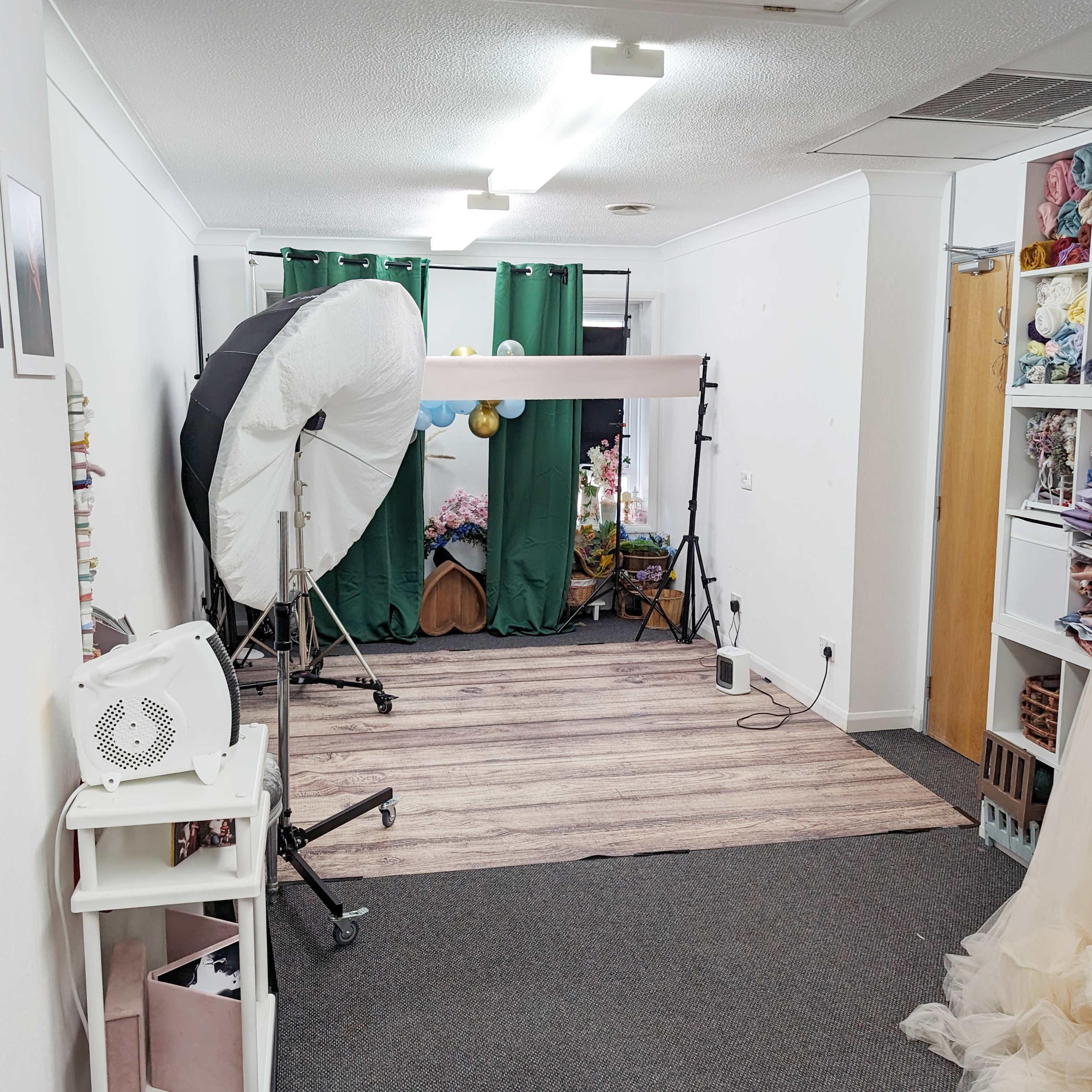 A photography studio with lighting equipment, a backdrop, and shelves filled with fabric.