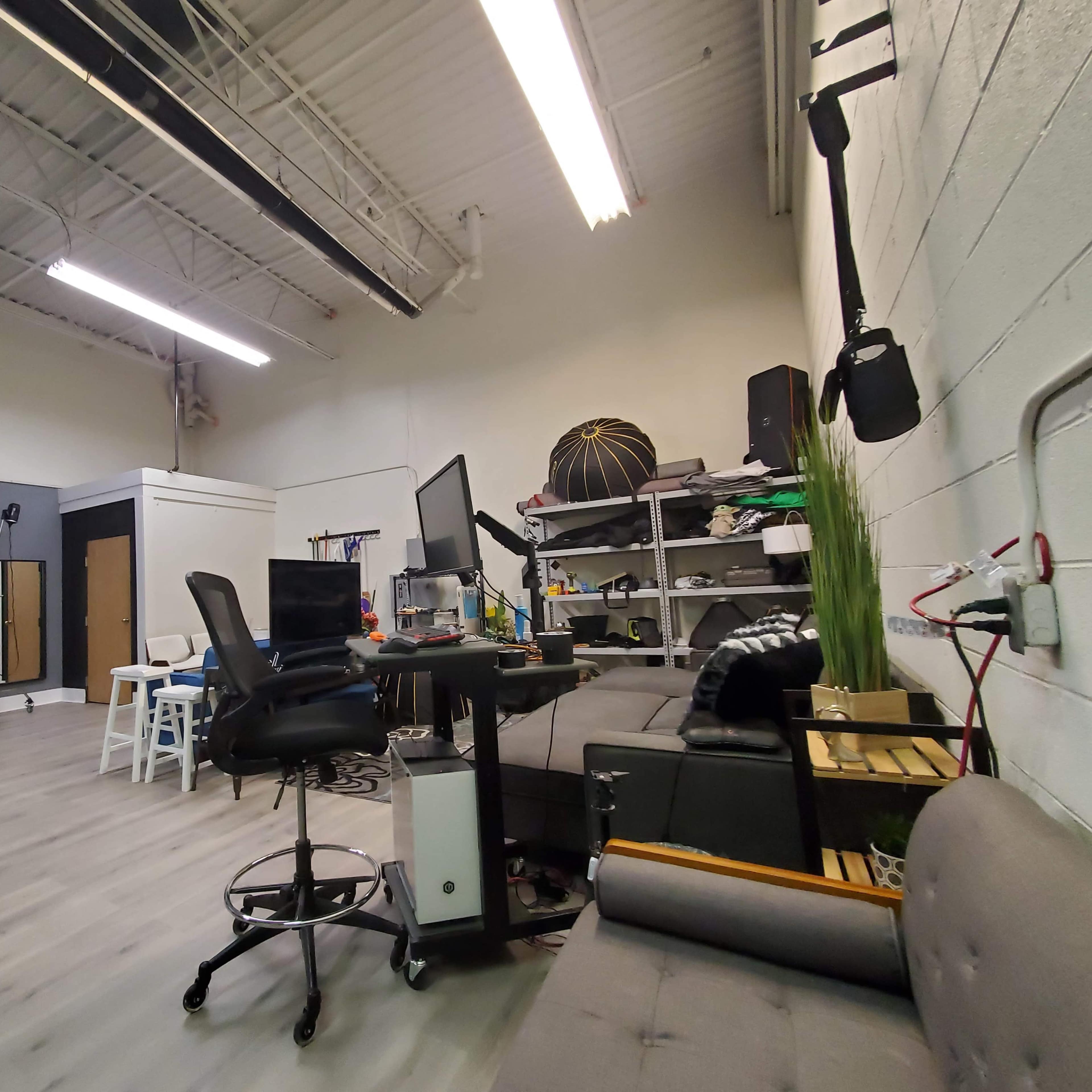 A photography studio with a seating area, computer desks, and various equipment organized on shelves.