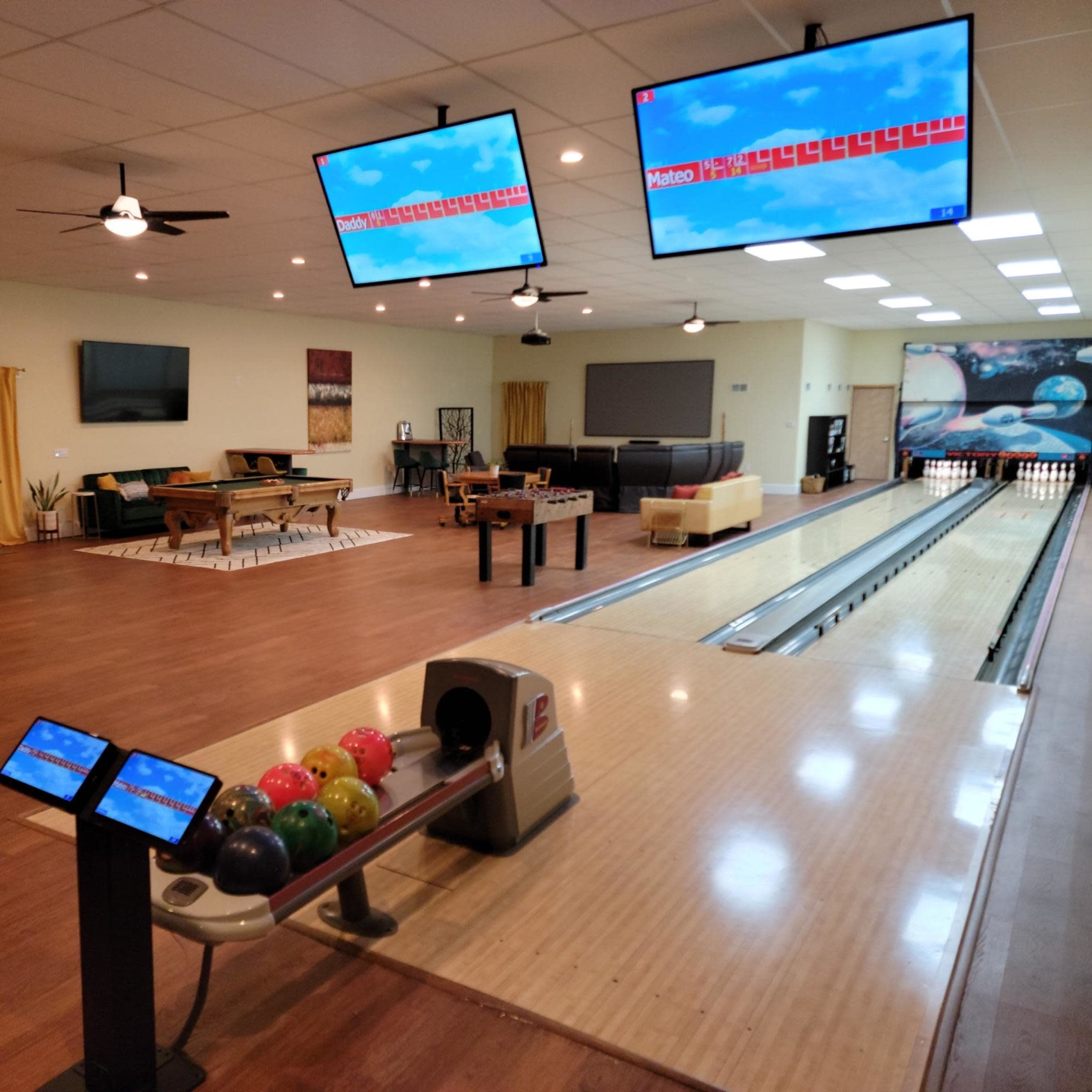 A modern bowling alley with multiple lanes, seating areas, and large screens displaying scores.