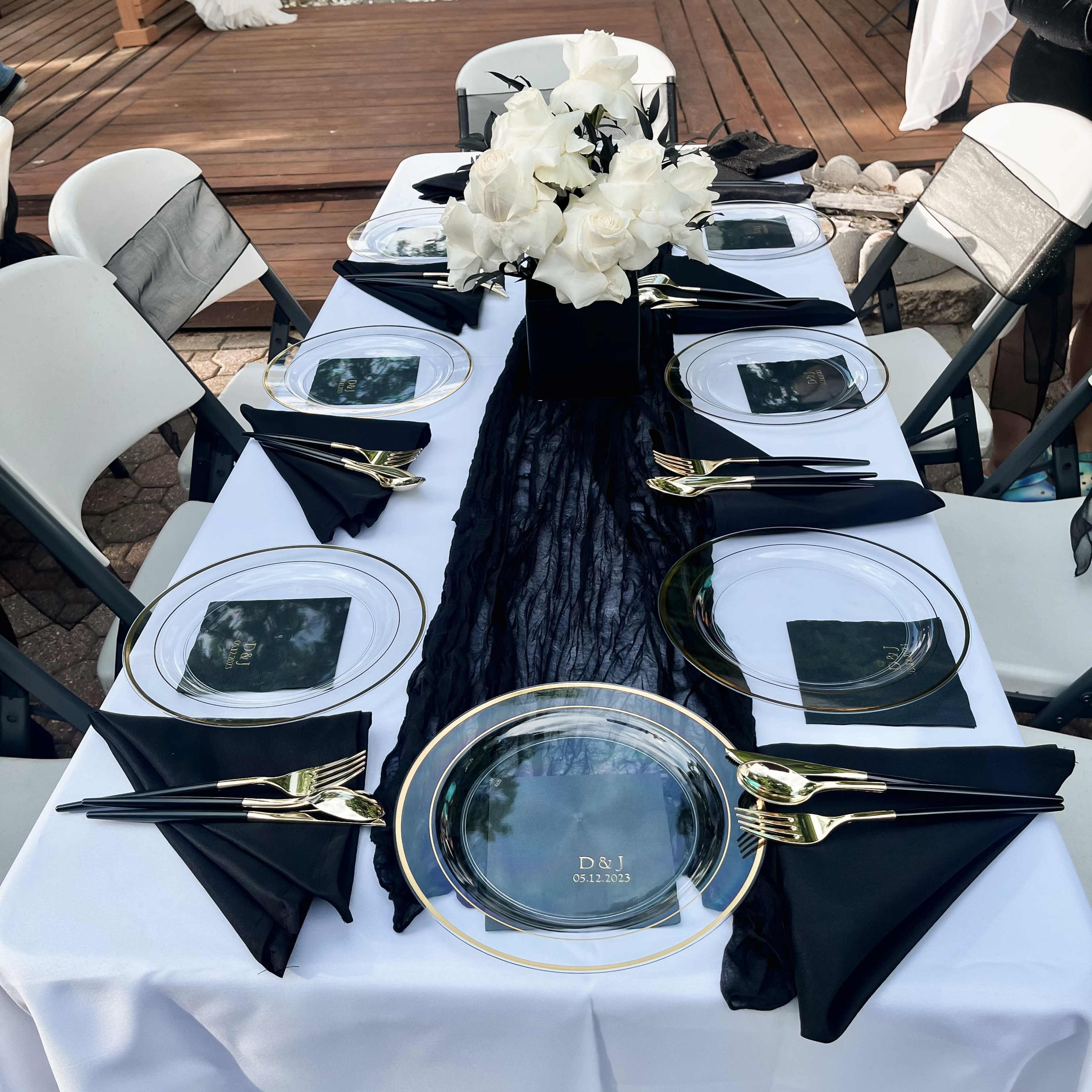A neatly arranged dining table features black and white decor with a centerpiece of white roses.