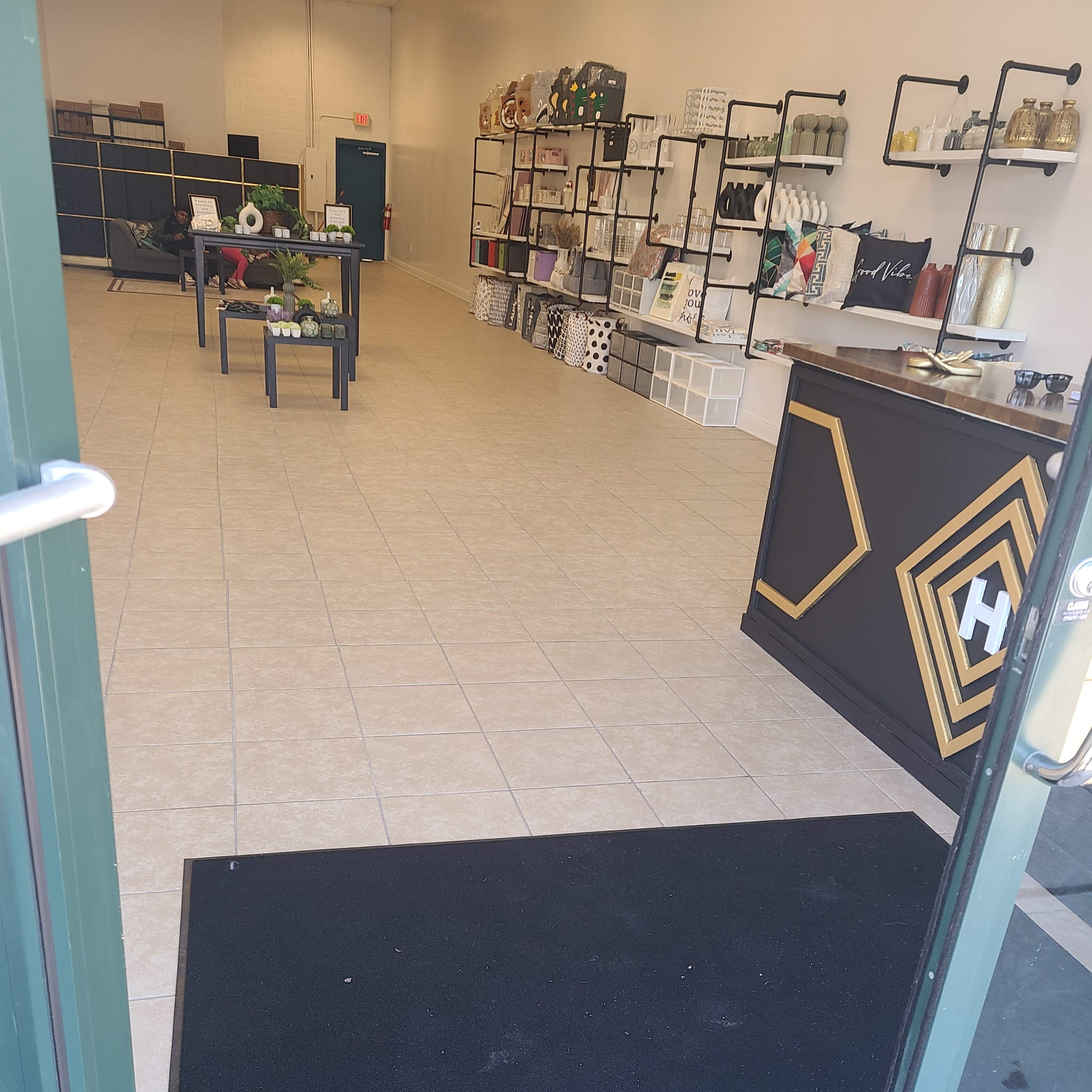 The interior of a retail space, featuring tiled floors, shelves with various items, and a counter near the entrance.