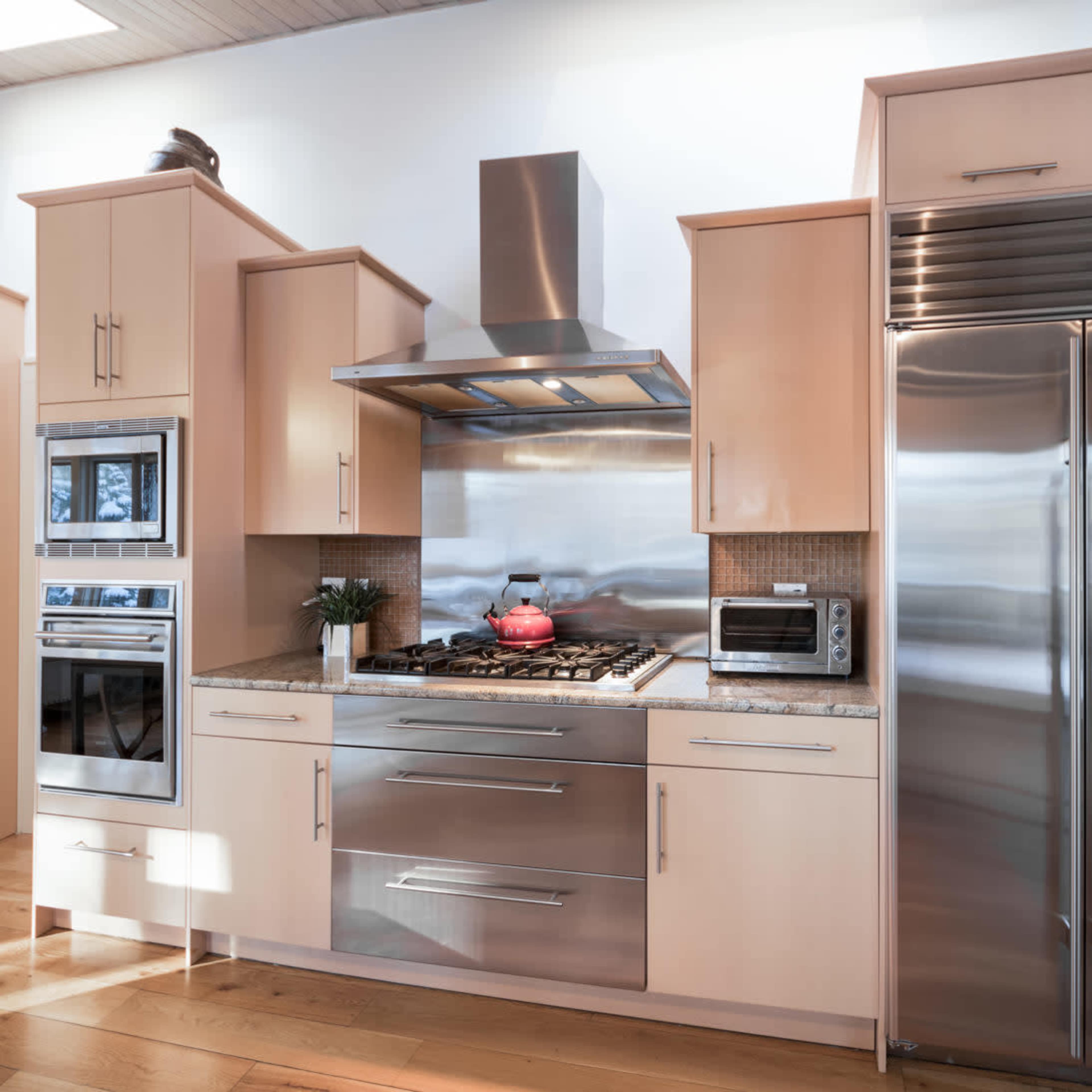 A modern kitchen with stainless steel appliances, wooden cabinetry, and a granite countertop.