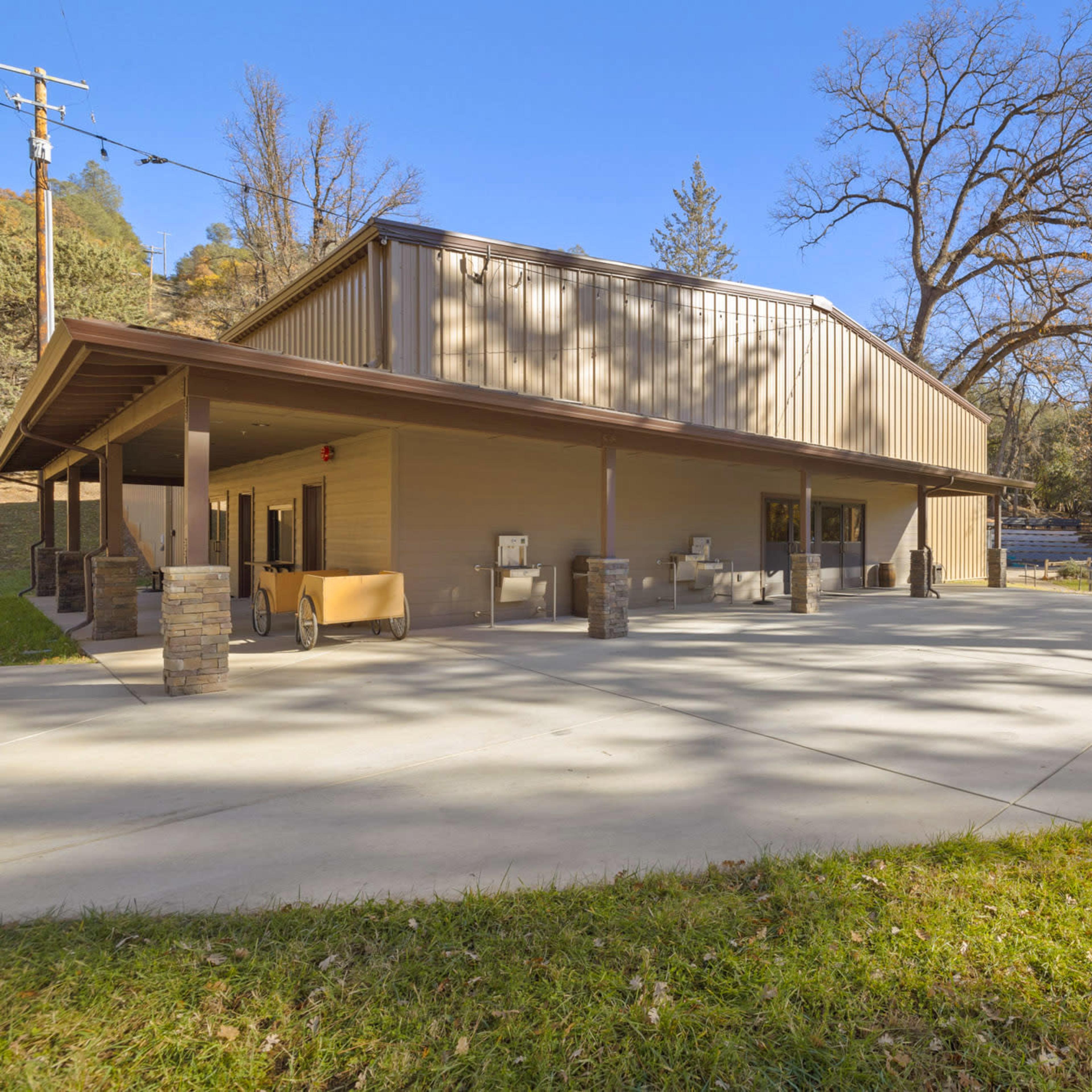 A large, modern building with an outdoor patio area surrounded by trees and a grassy lawn.