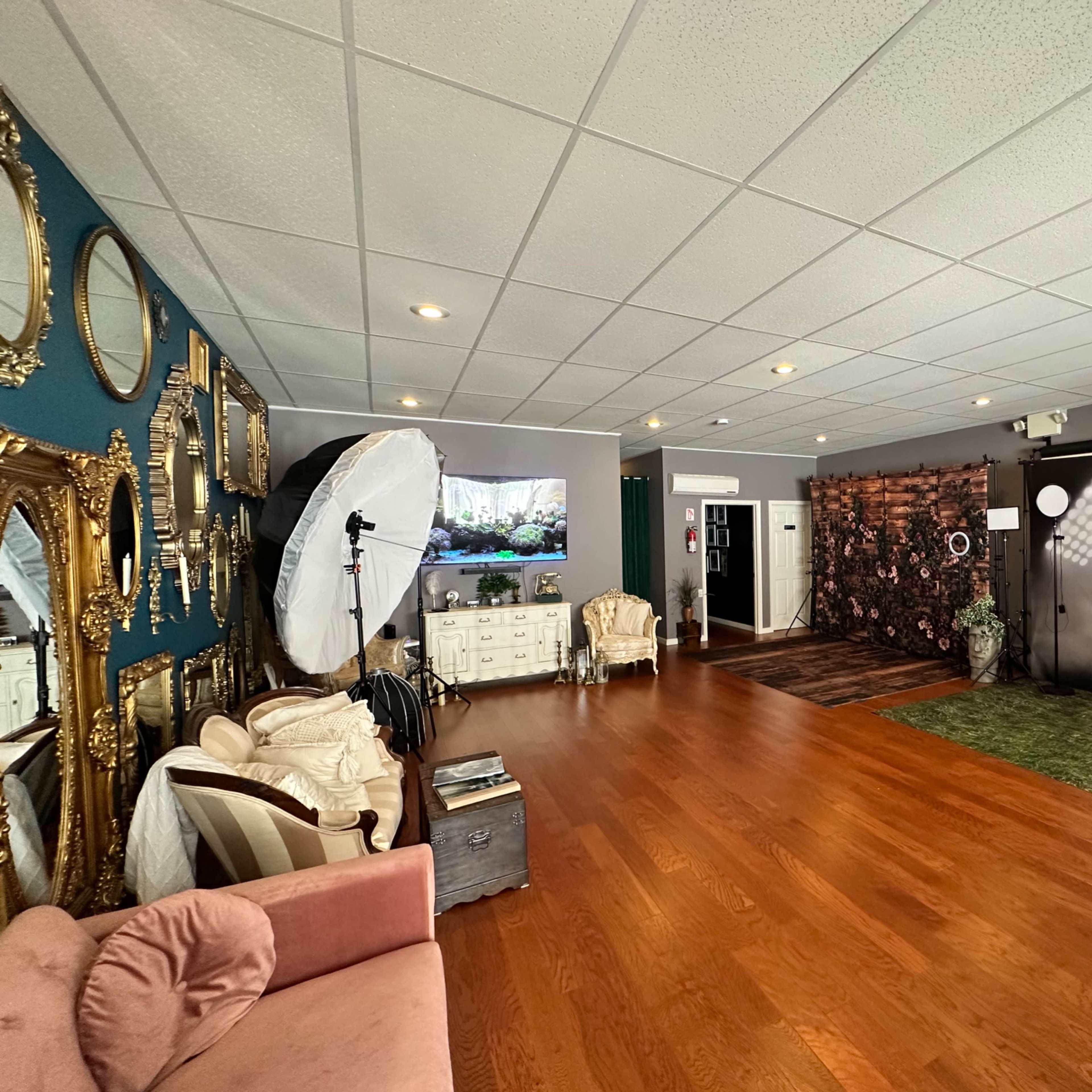 A spacious, well-lit photography studio with decorative mirrors, a variety of backdrops, and equipment set up for photo shoots.