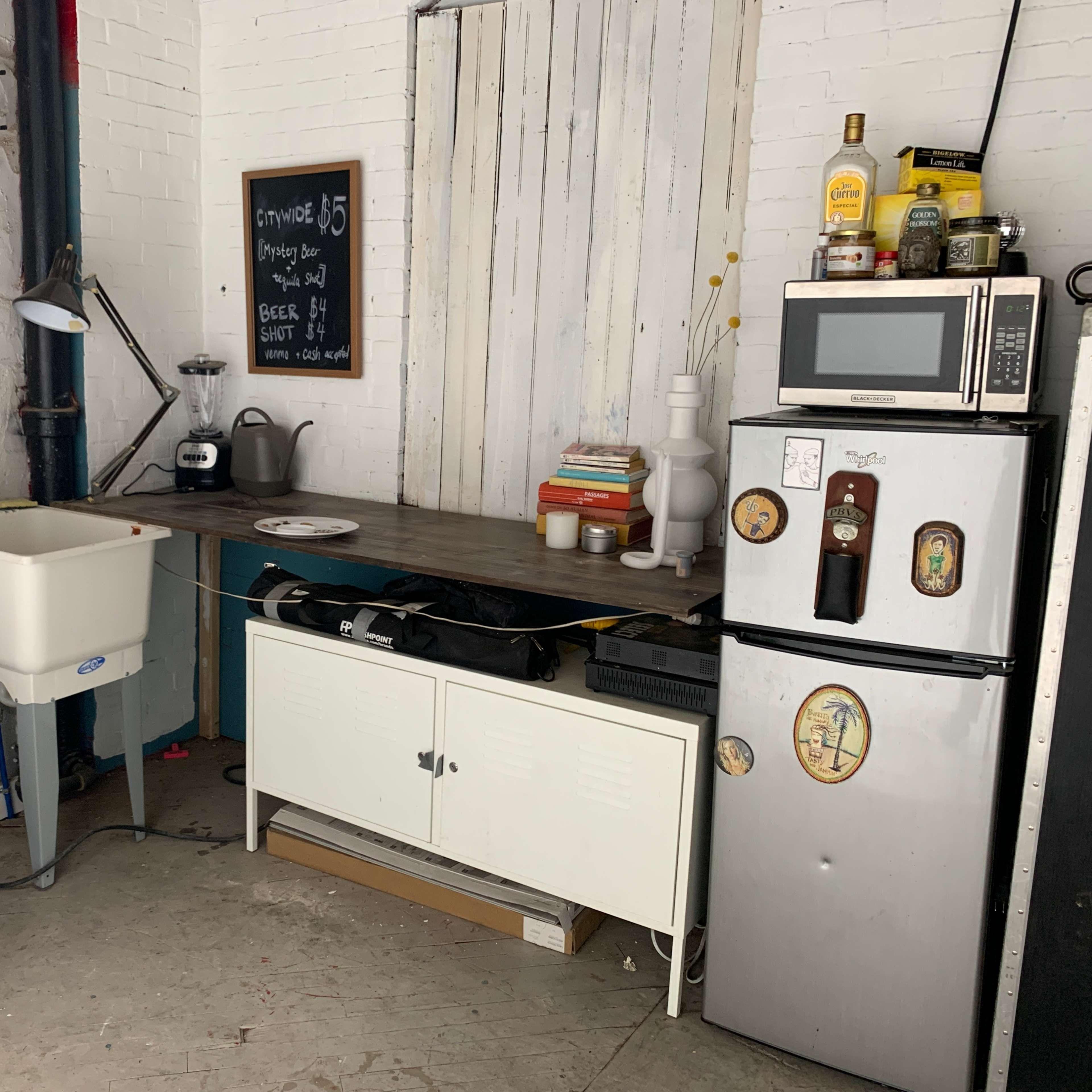 A kitchen area with a wooden countertop, a sink, a microwave, and a fridge, along with various kitchen appliances and utensils.