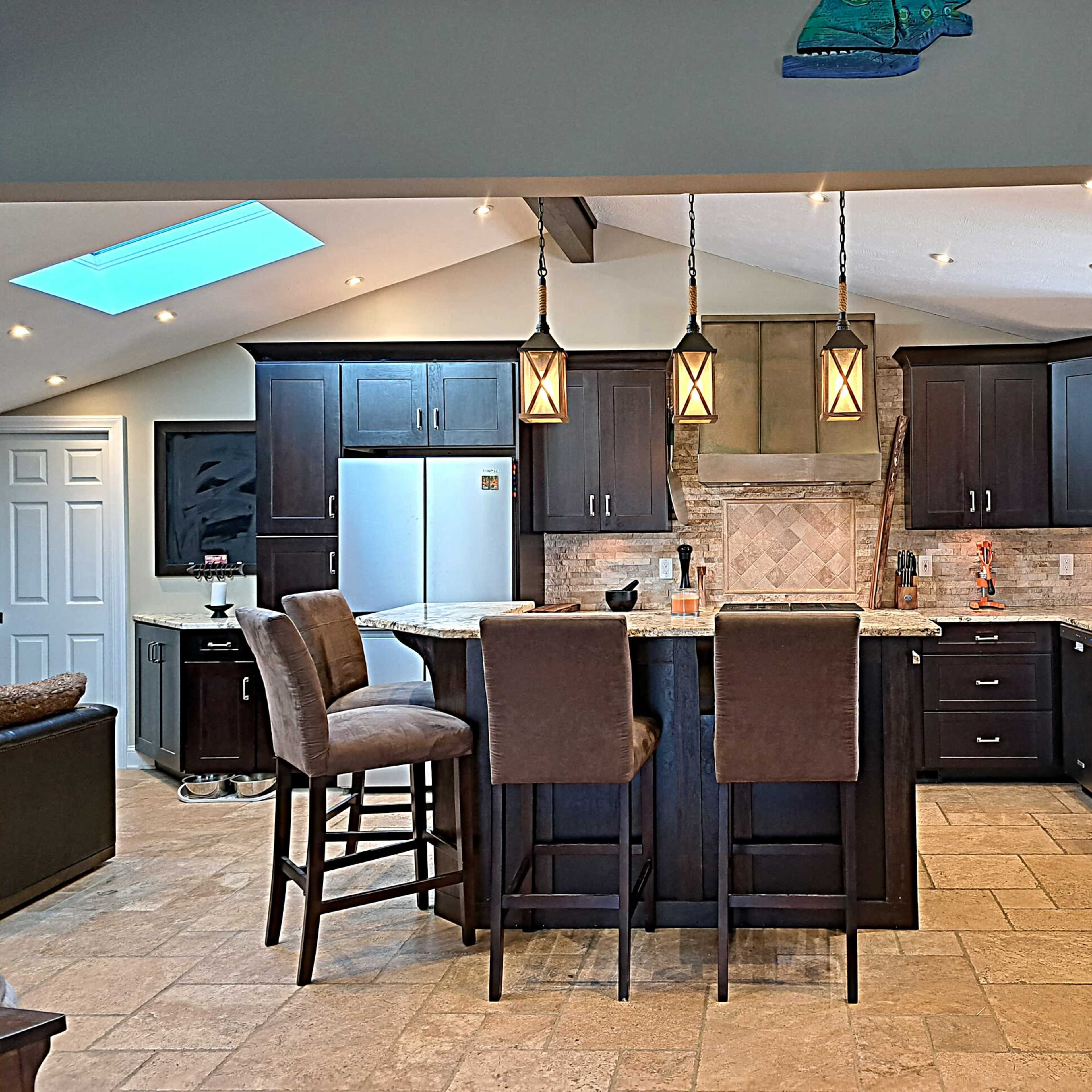 A modern kitchen with dark wooden cabinetry, granite countertops, and a large island with bar seating.