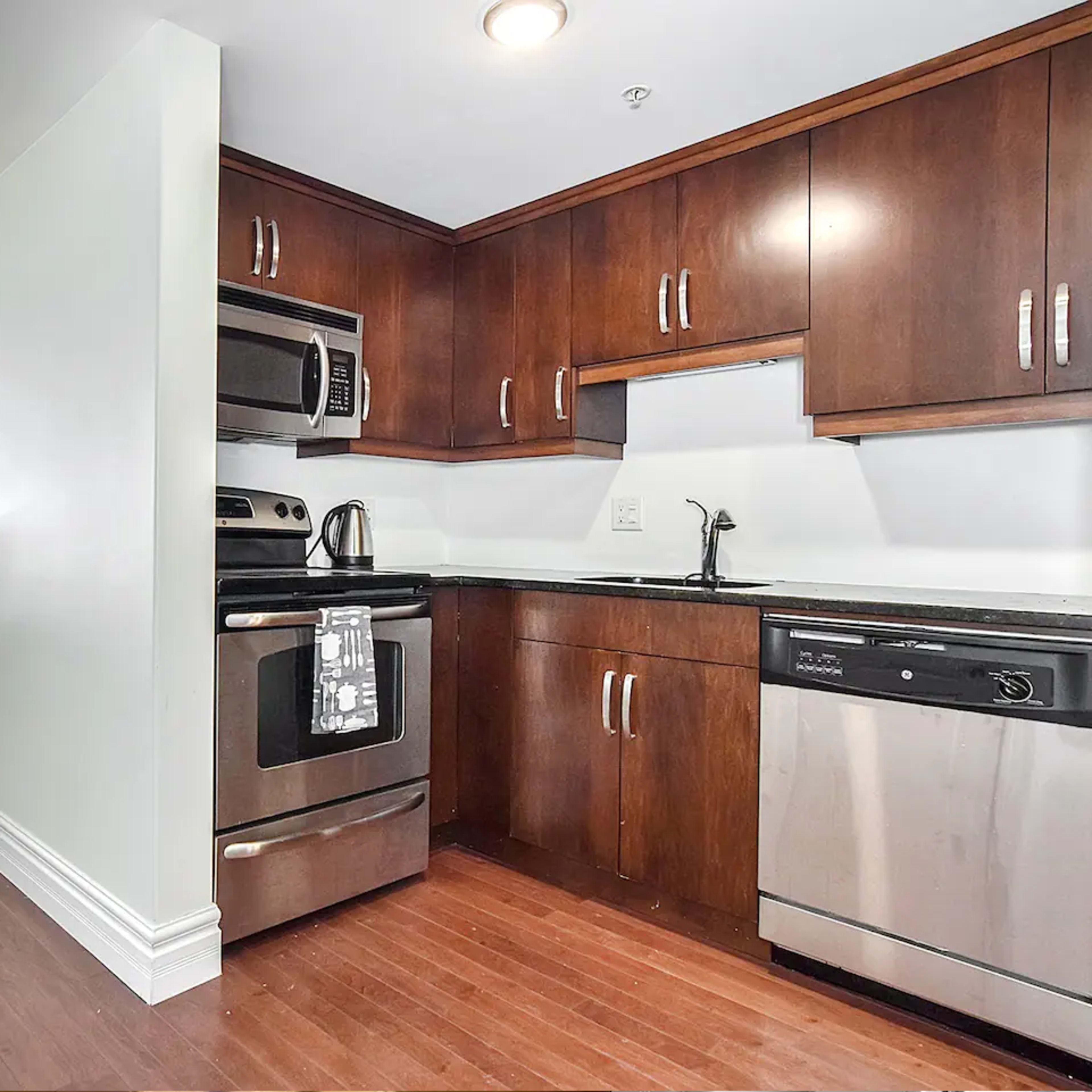 A modern kitchen with dark wood cabinets, stainless steel appliances, and a small plant on the counter.