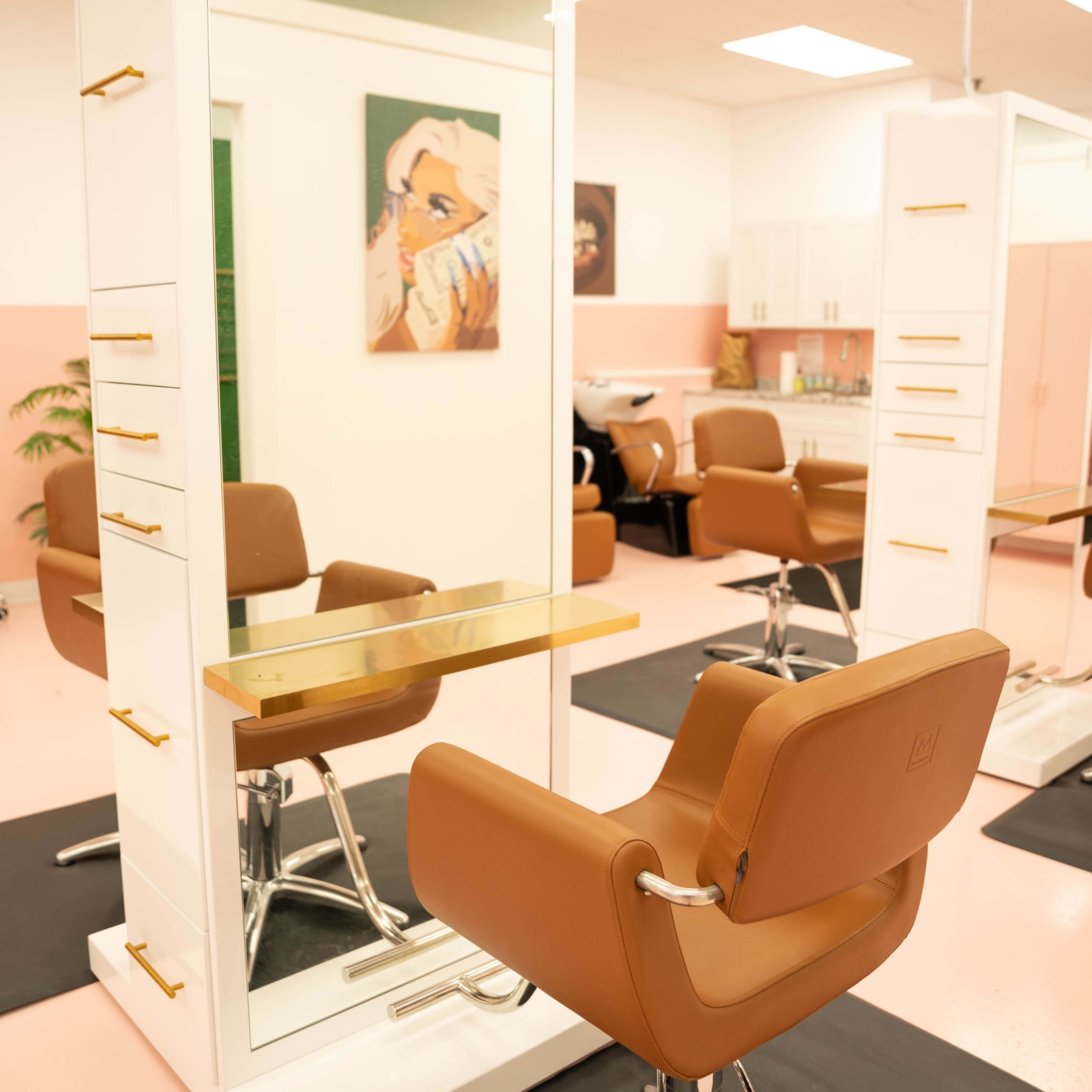 A modern hair salon with stylist stations featuring mirrors, elegant chairs, and a pink and white color scheme.