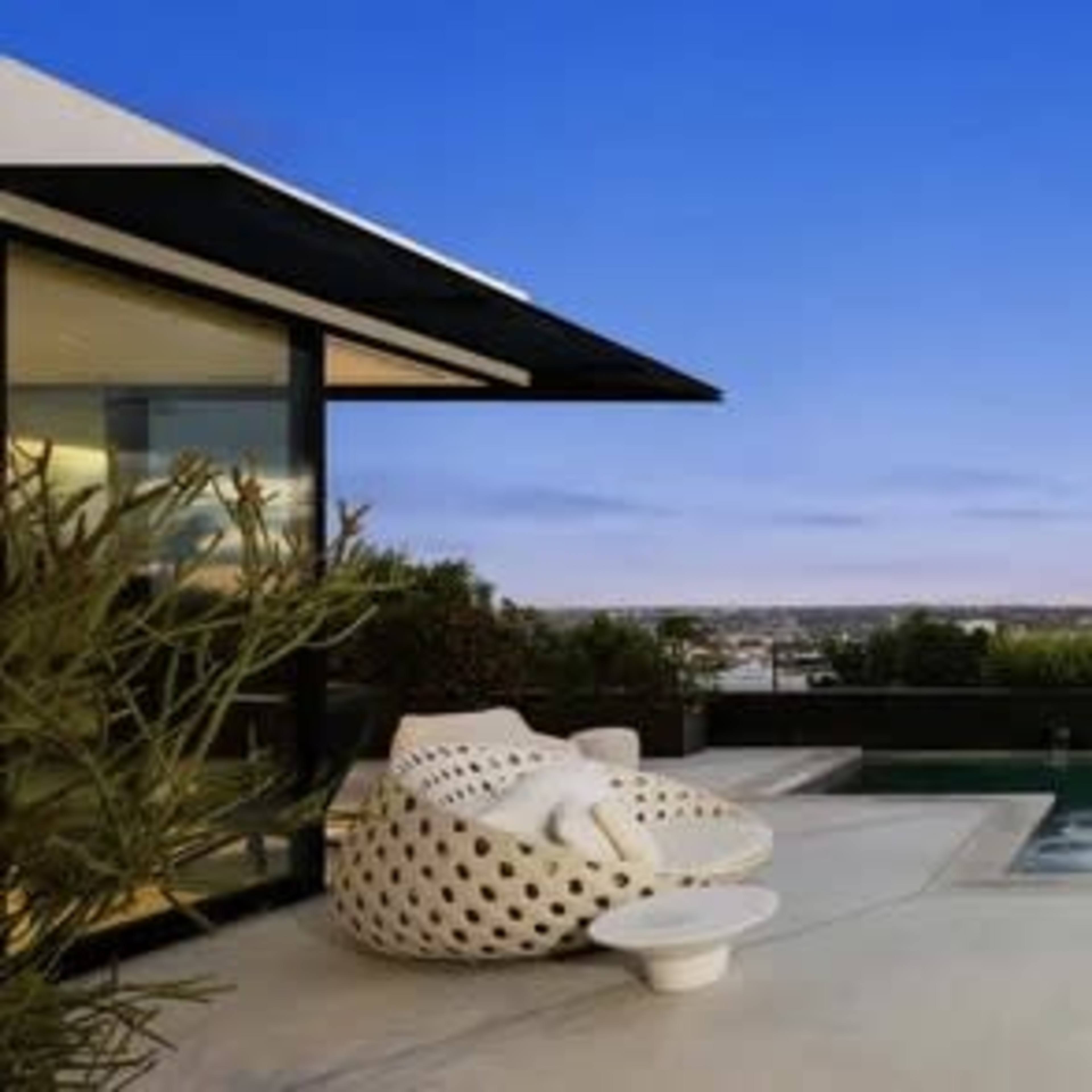 A modern outdoor space featuring a pool surrounded by minimalist landscaping and seating areas at dusk.