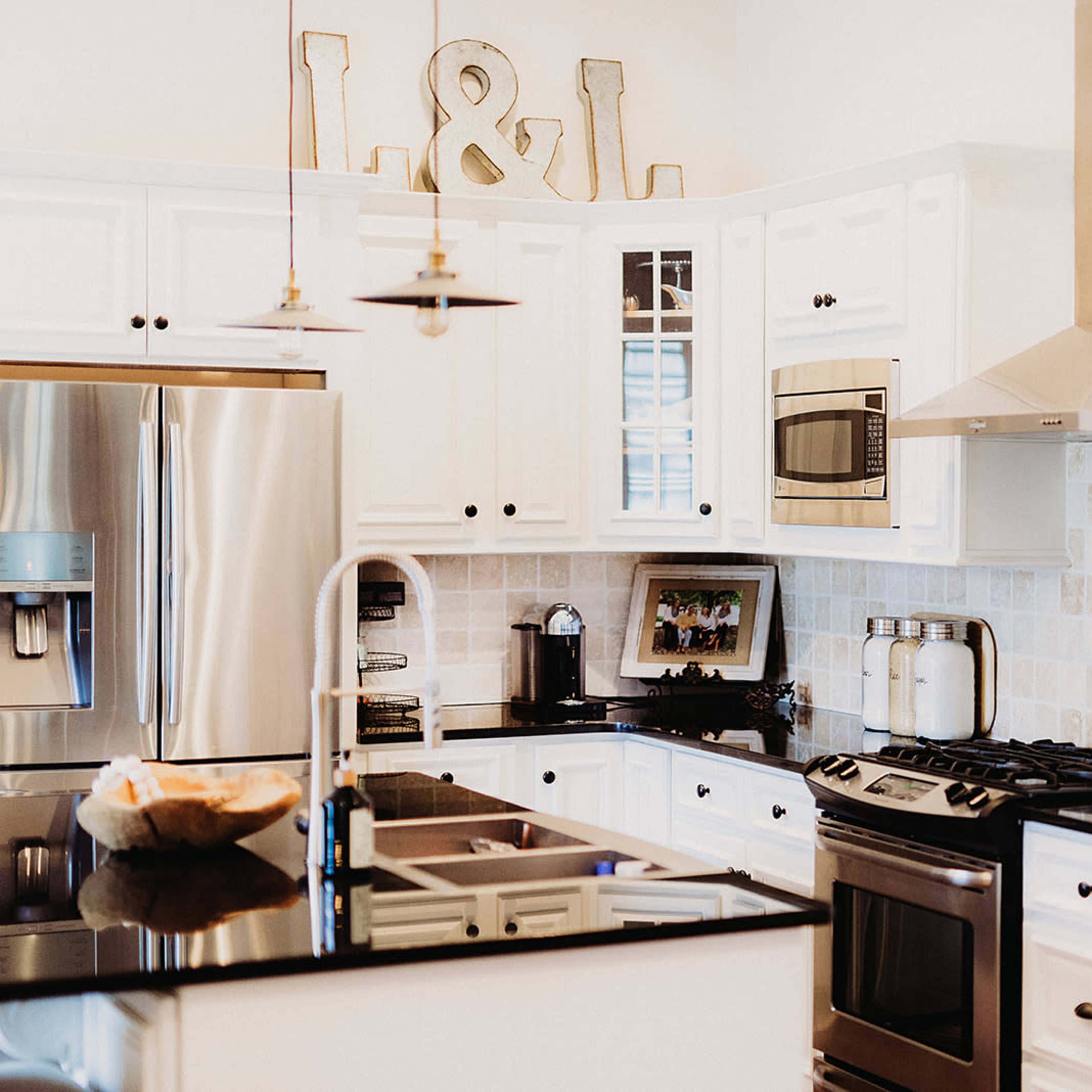 A modern kitchen with white cabinetry, black countertops, and stainless steel appliances.