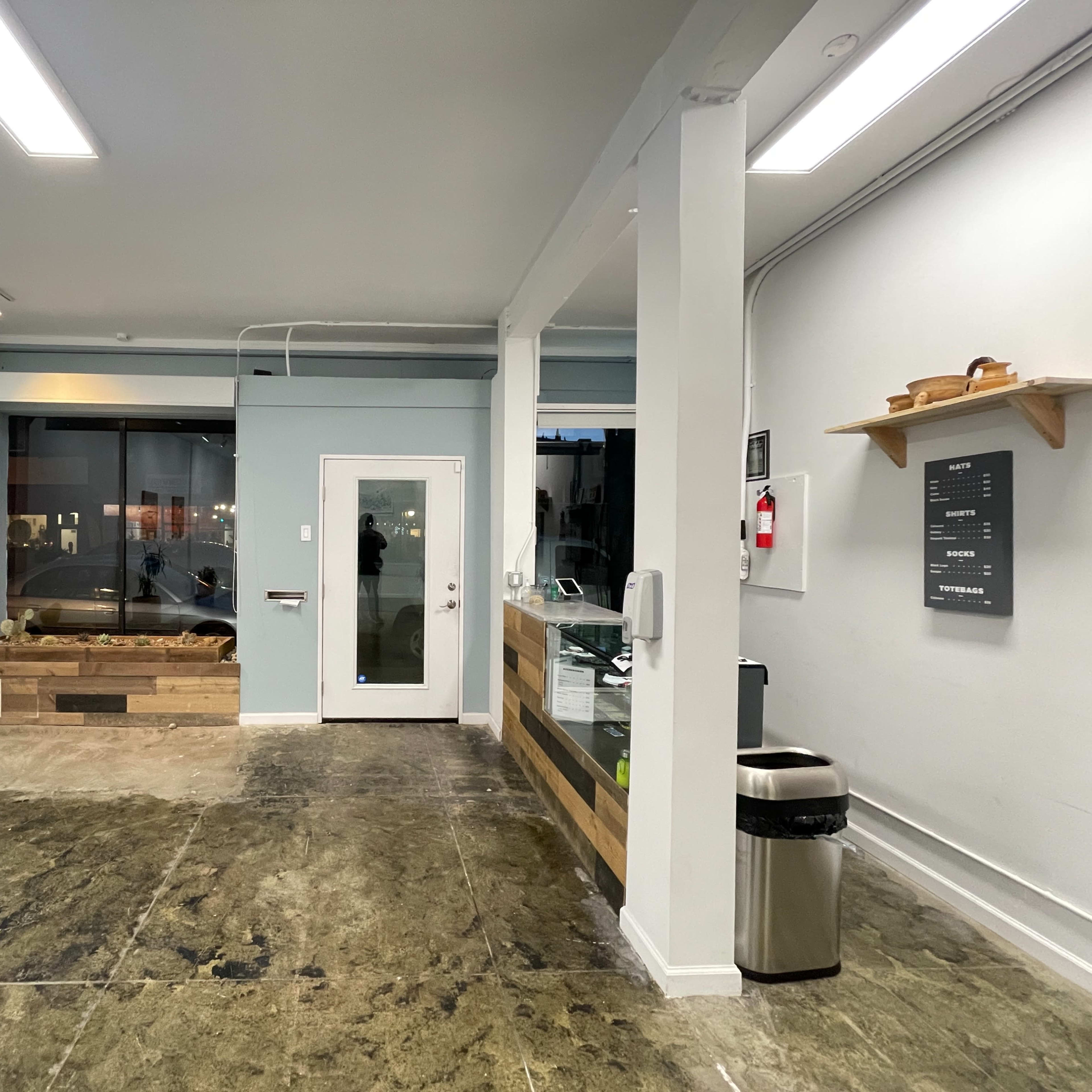 A spacious, minimalistic interior of a commercial space with a reception area, a large window, and a door leading outside.