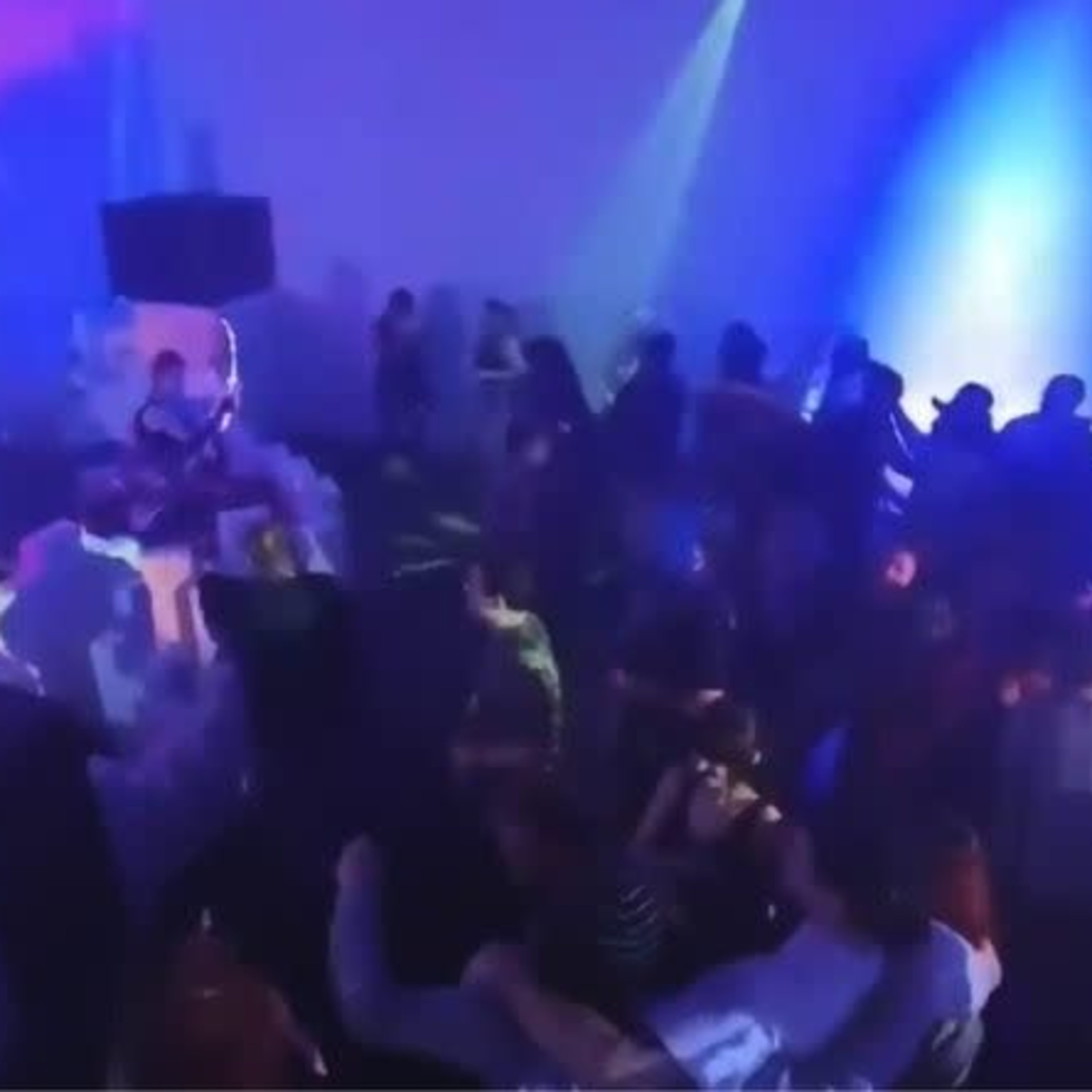 A lively indoor party scene features a crowd dancing under colorful lights.