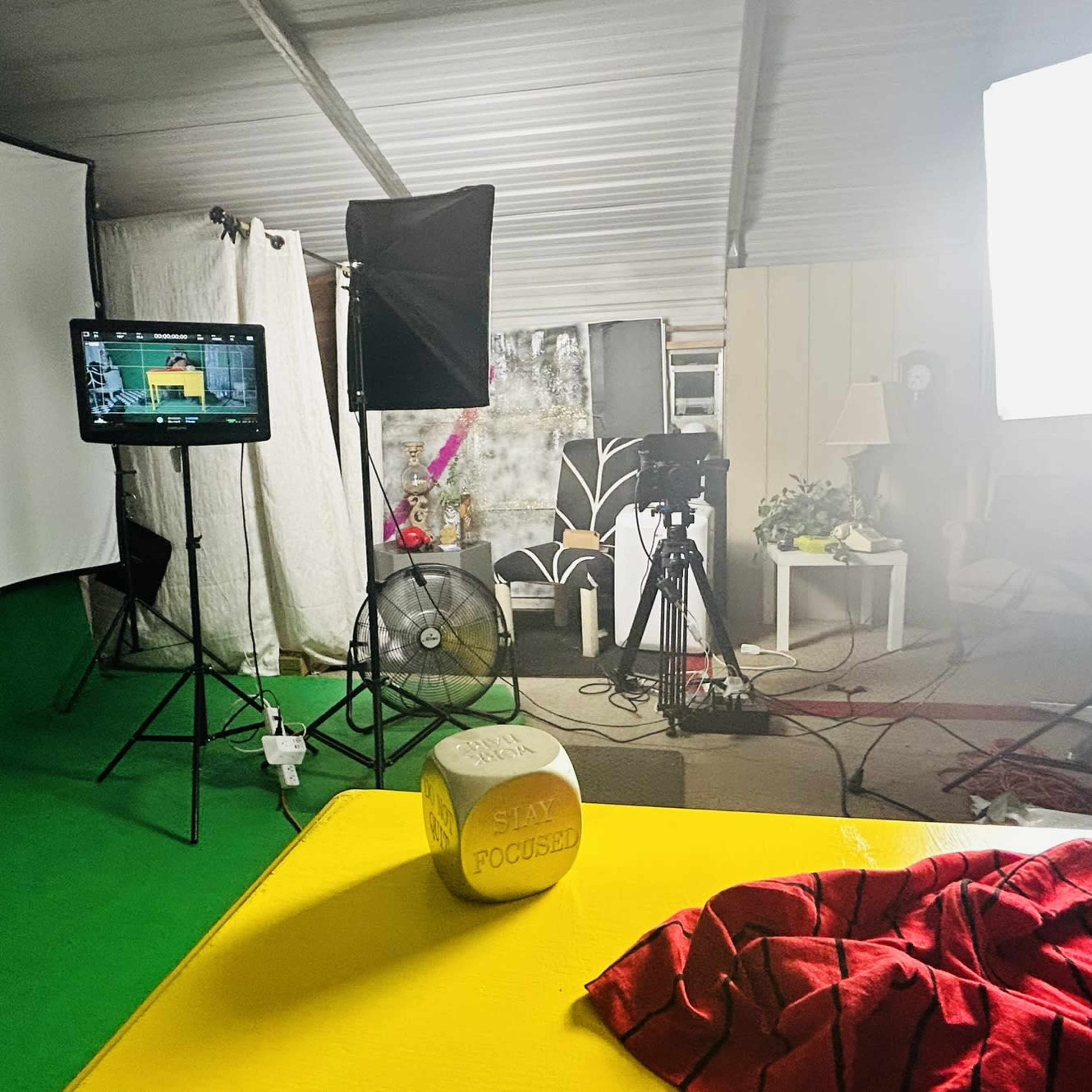 A photography studio setup with lighting equipment, a backdrop, and a table displaying a shirt and a wooden block labeled "FOCUSED."