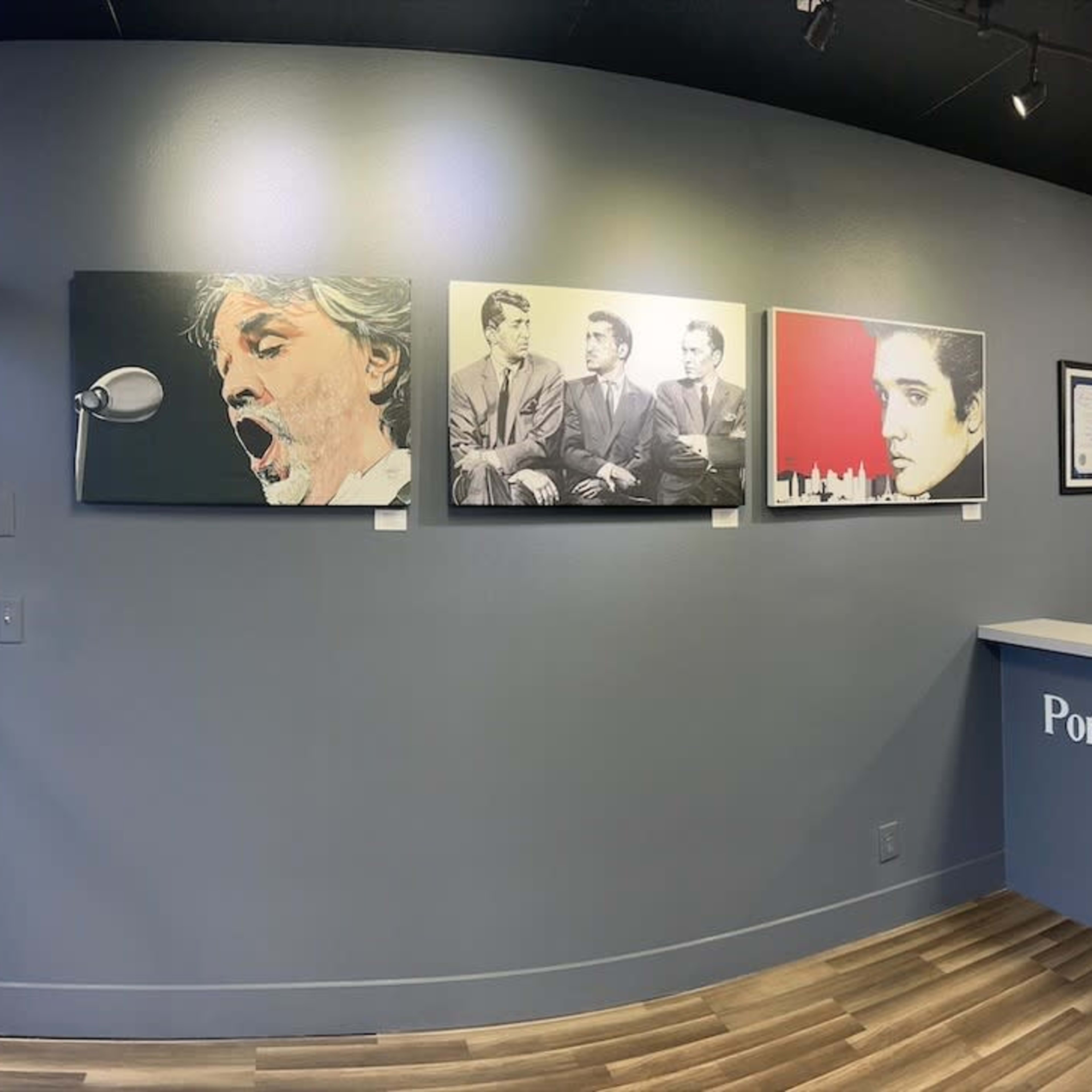 The interior of a gallery featuring walls adorned with various artworks, a reception desk, and seating for visitors.
