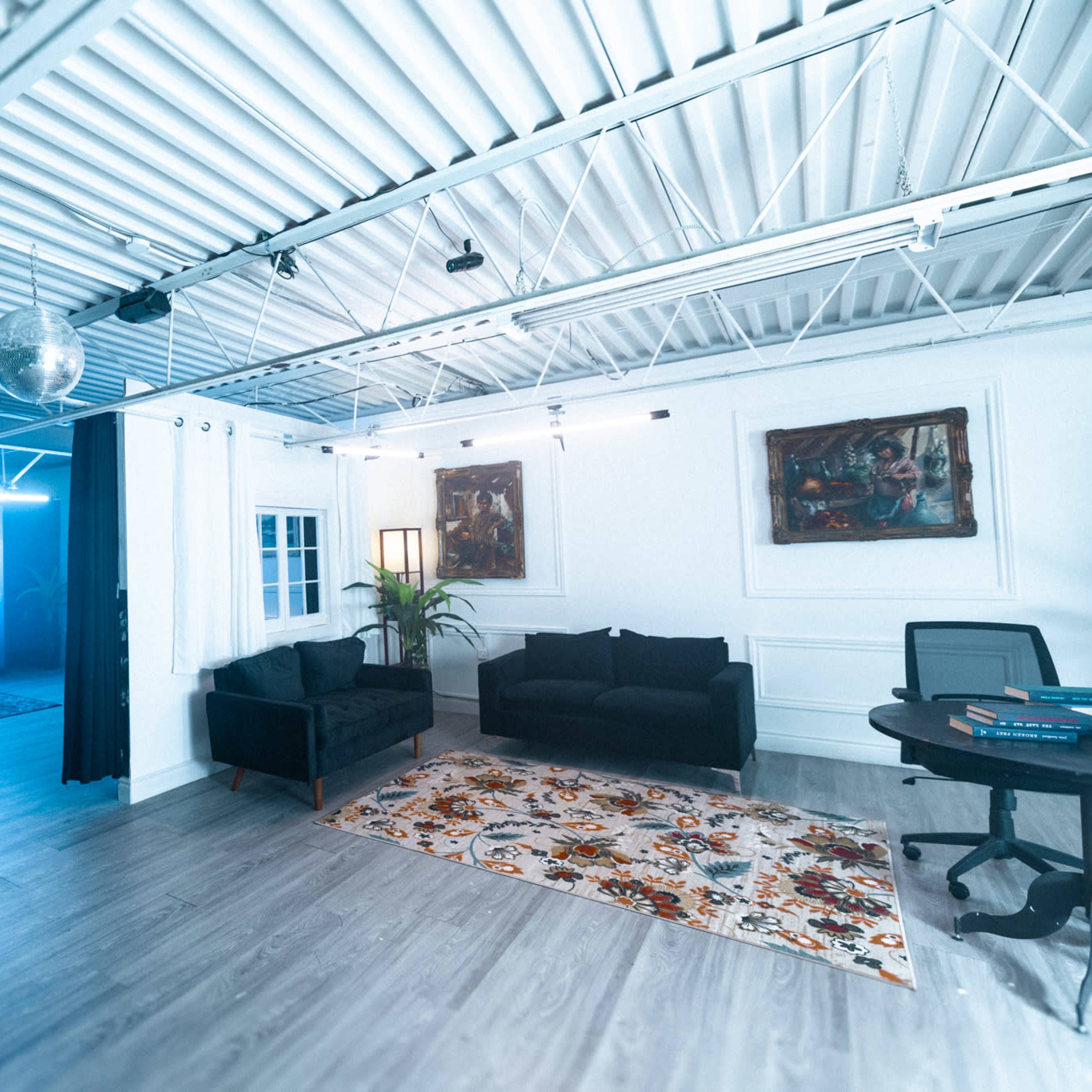 A modern office space features a seating area with dark couches, a large decorative rug, and a backdrop of a celestial-themed mural.