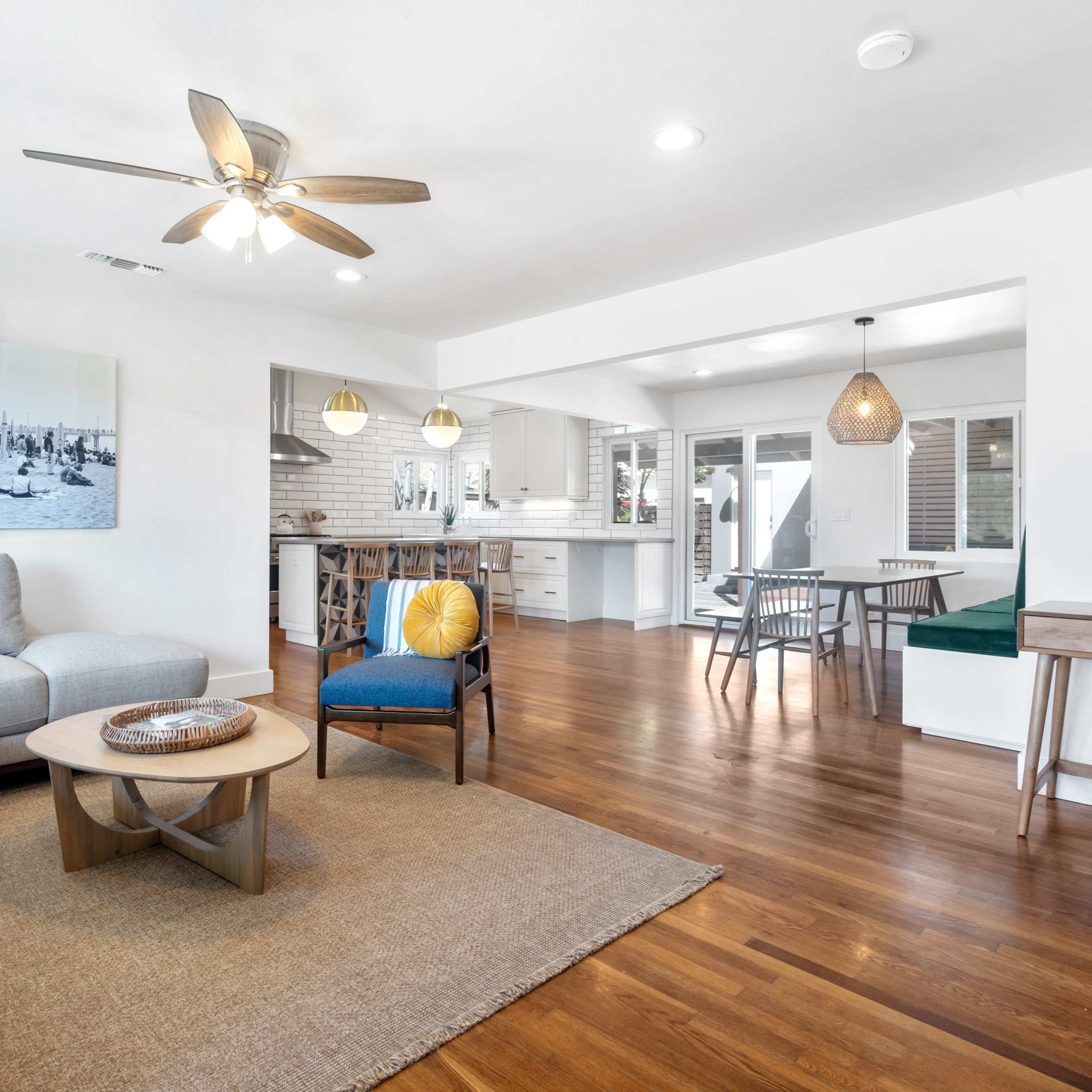A bright, open-concept living area combined with a dining space, featuring modern furniture and hardwood flooring.