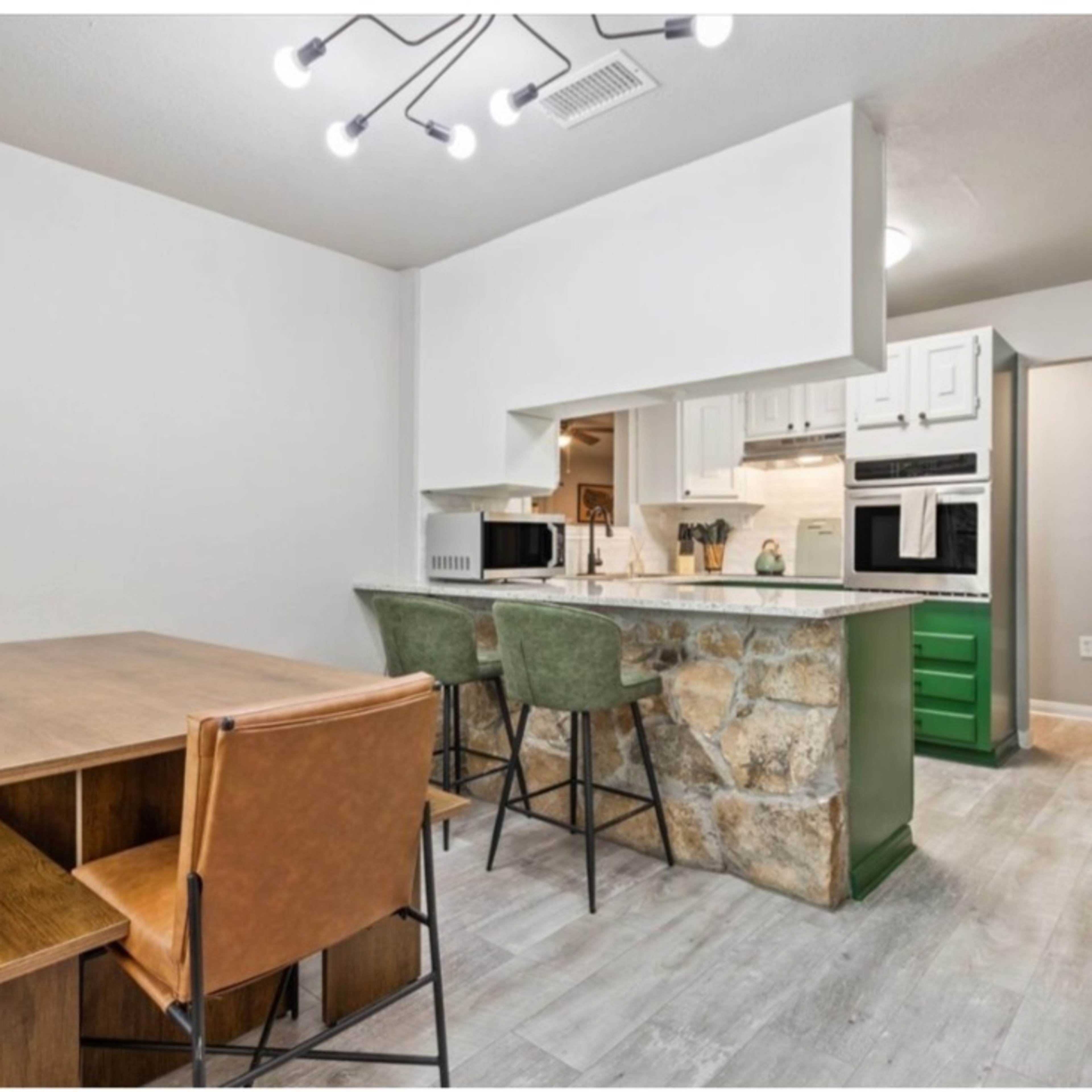 A modern kitchen with a stone-accented island, a dining table, and four chairs.