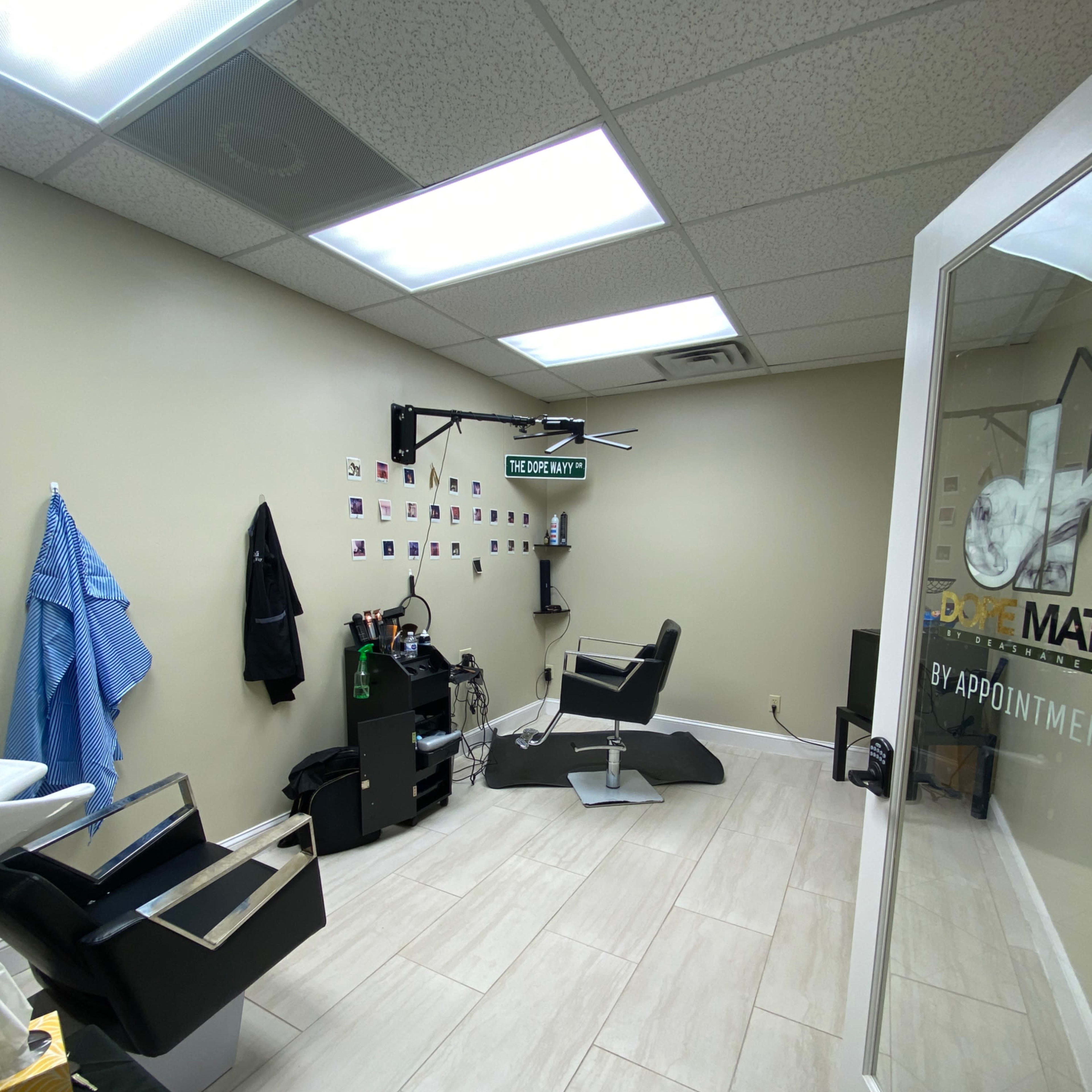 A modern barbershop interior with a styling chair, a large mirror, and a wall decorated with photographs.