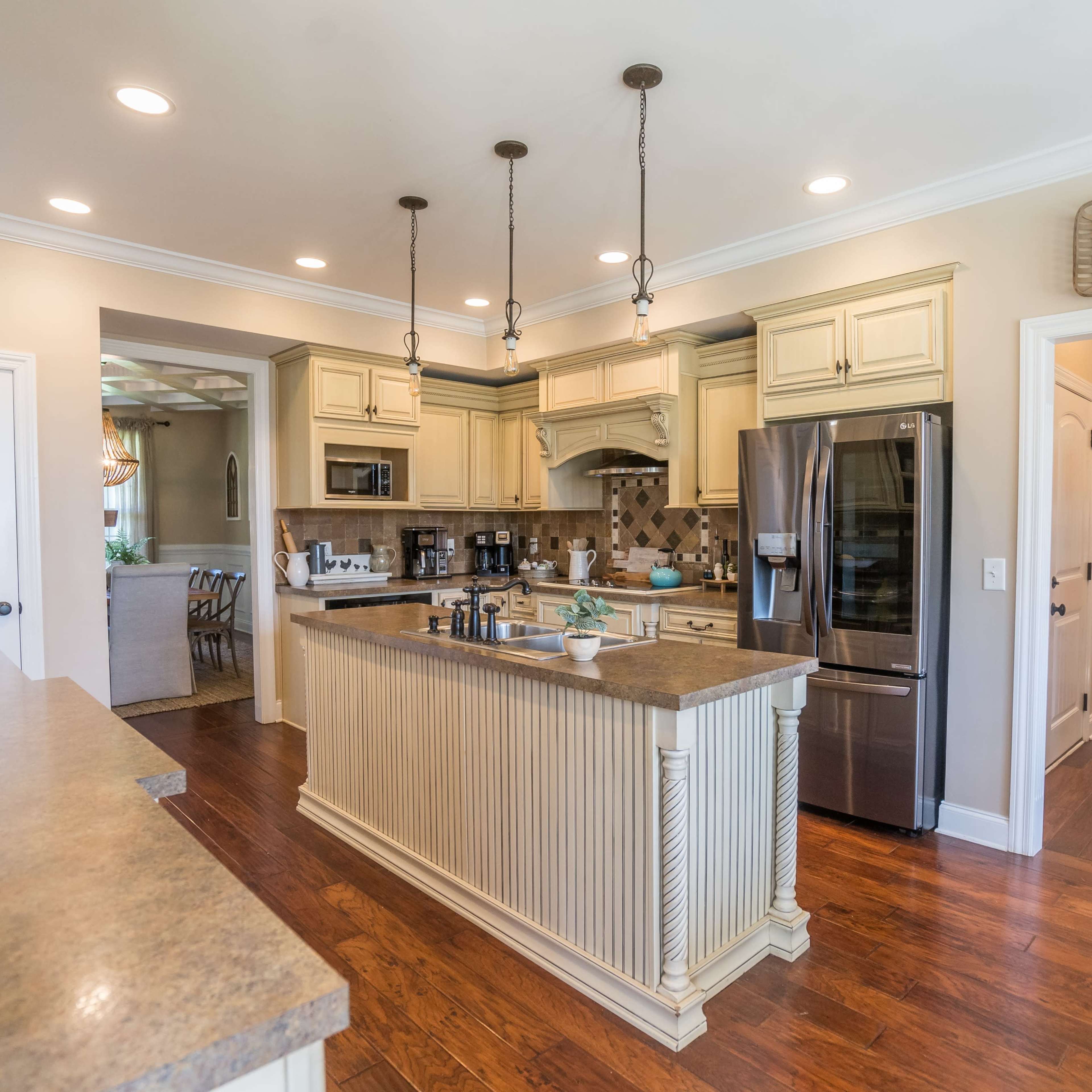 A spacious kitchen with a central island, stainless steel appliances, and pendant lighting above the countertop.