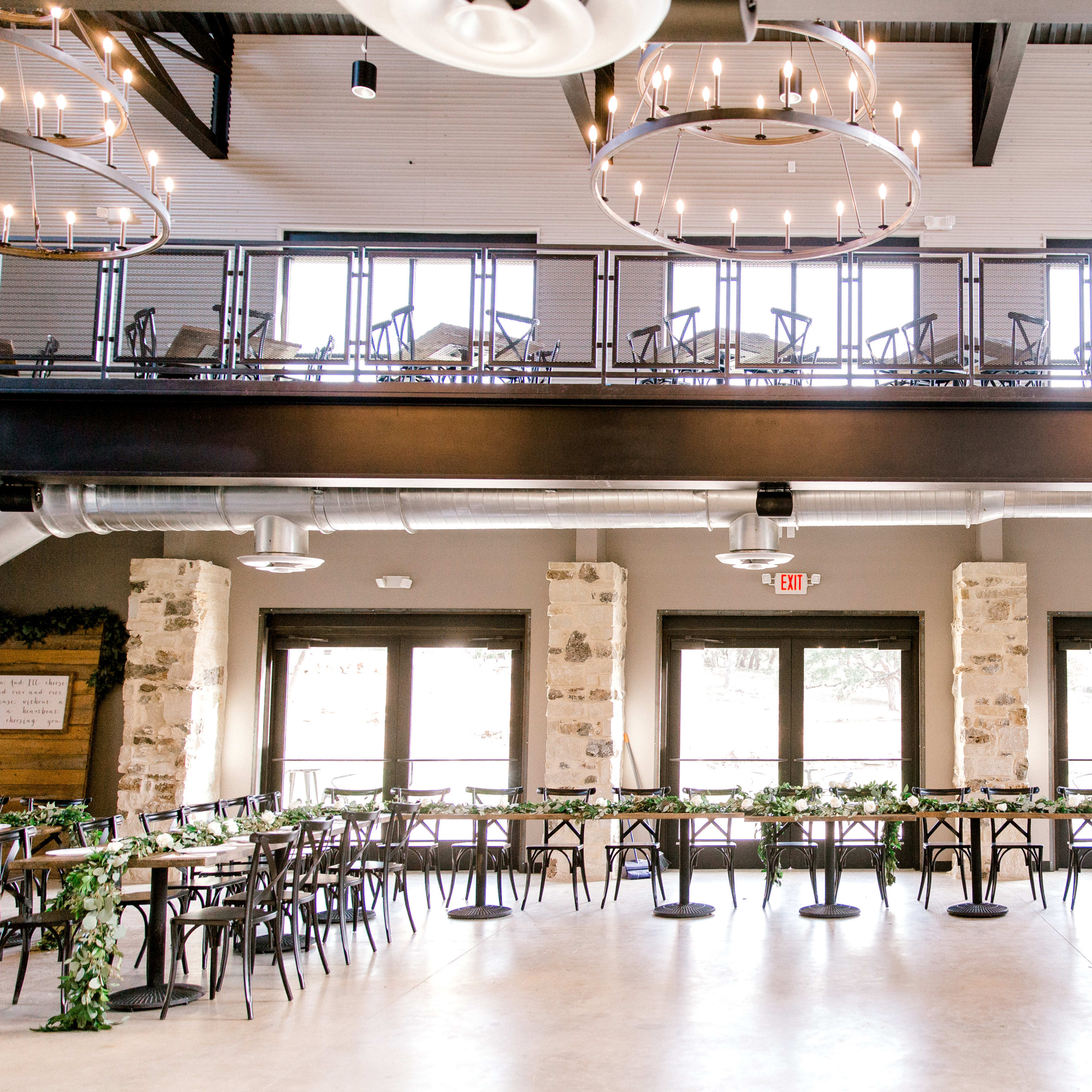 A dining area with rows of tables and chairs arranged neatly, featuring large windows and modern light fixtures.