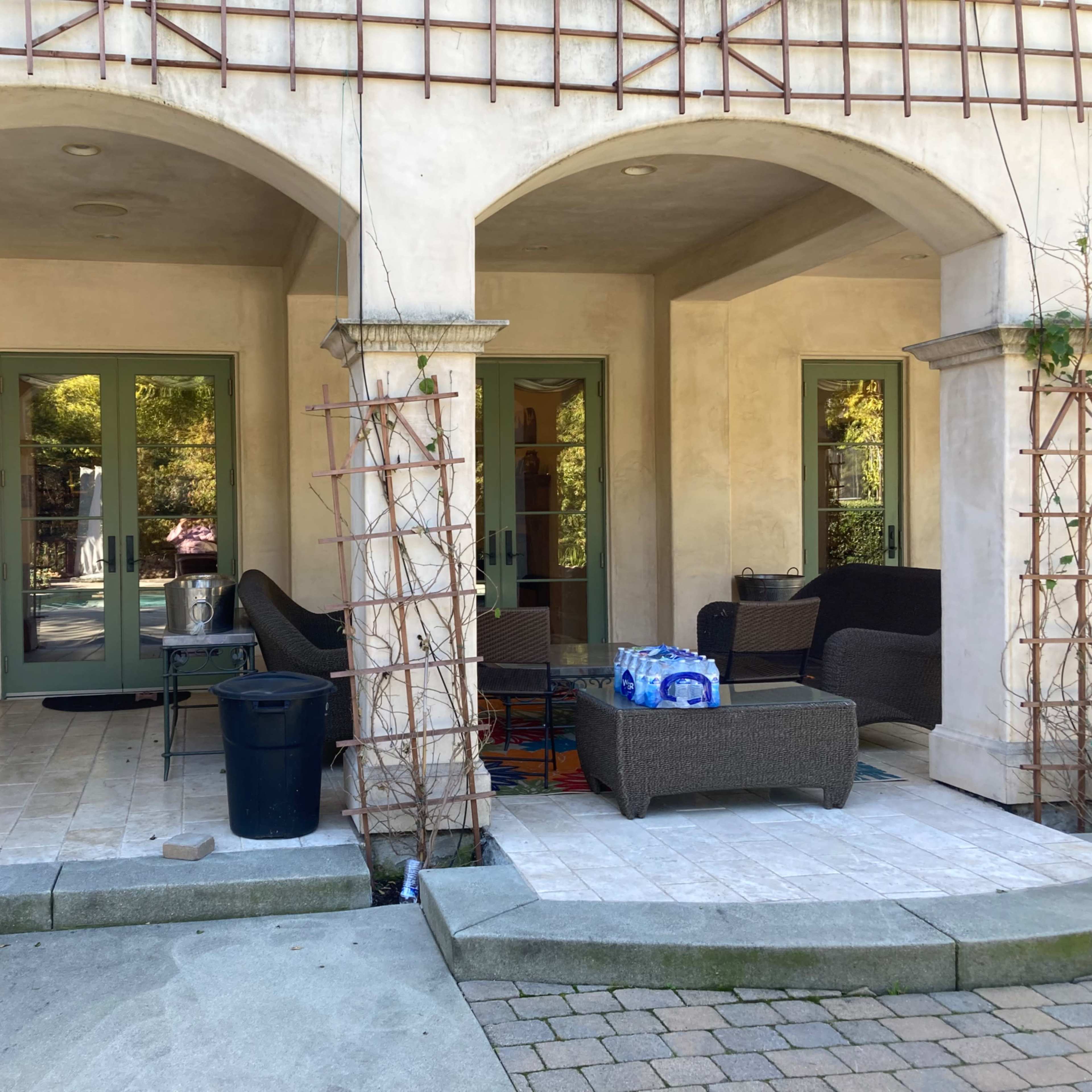 A patio area with arched entrances, featuring outdoor furniture and potted plants.