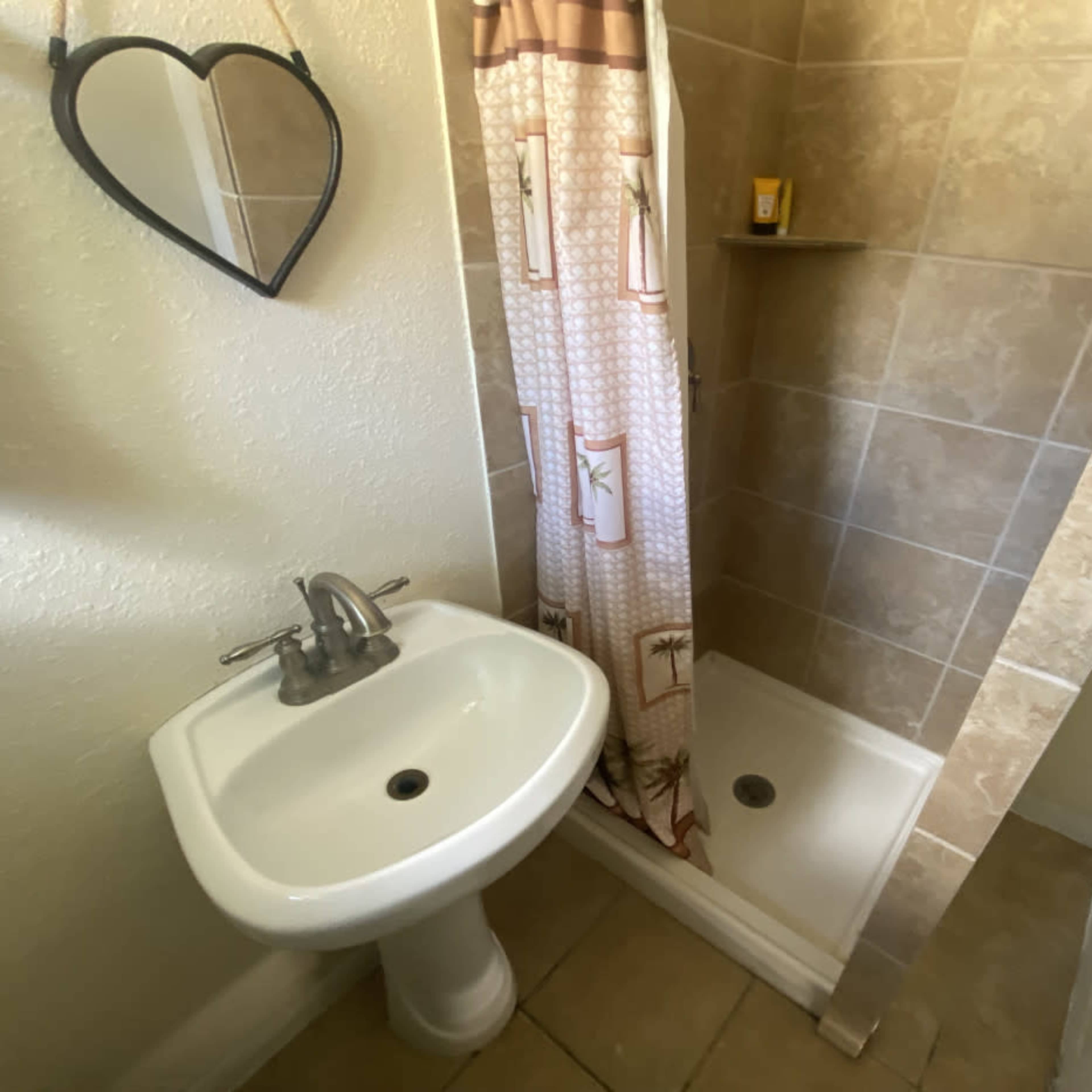 A small bathroom featuring a sink and a shower stall with a curtain.