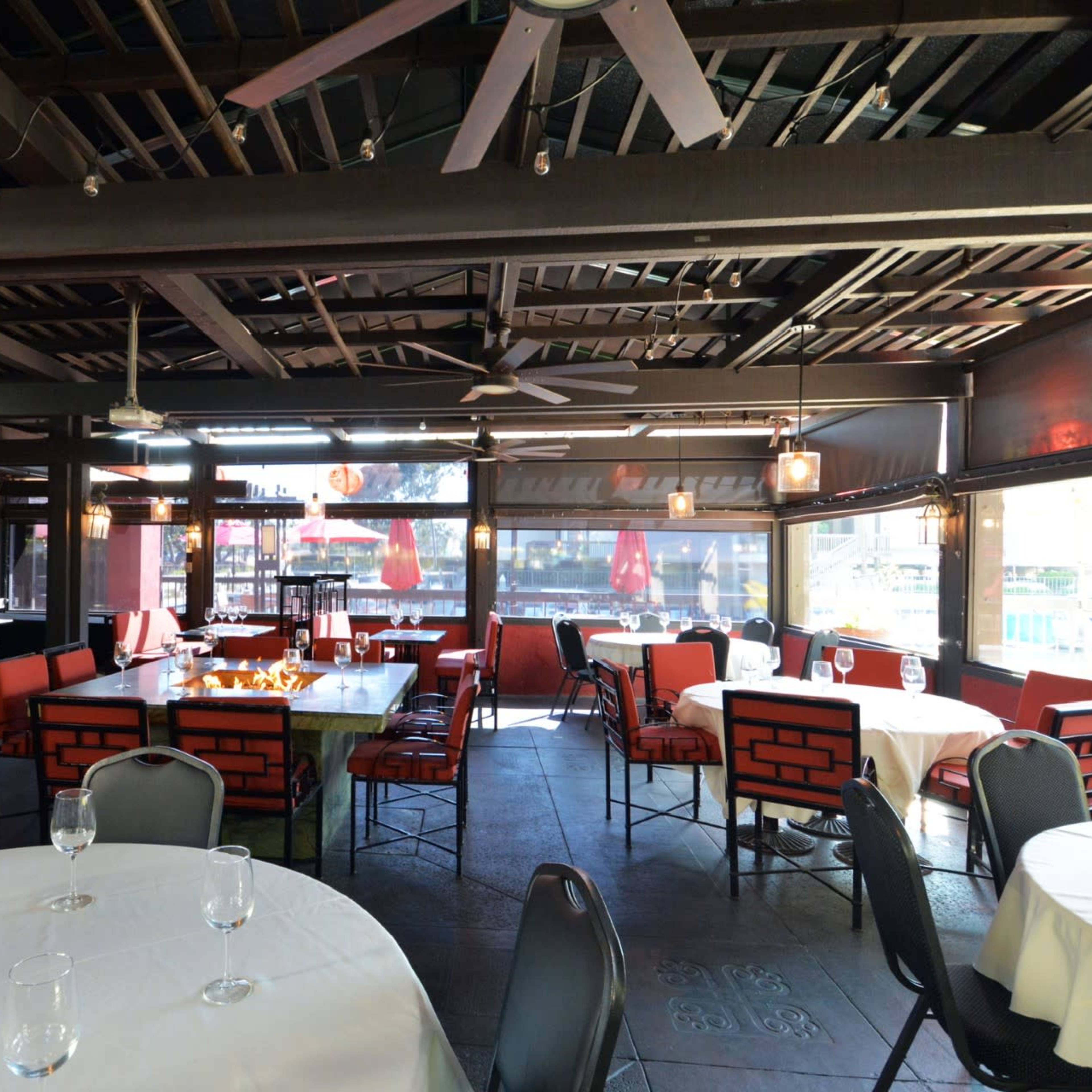 A spacious dining area with tables set for guests, featuring large windows and decorative light fixtures.