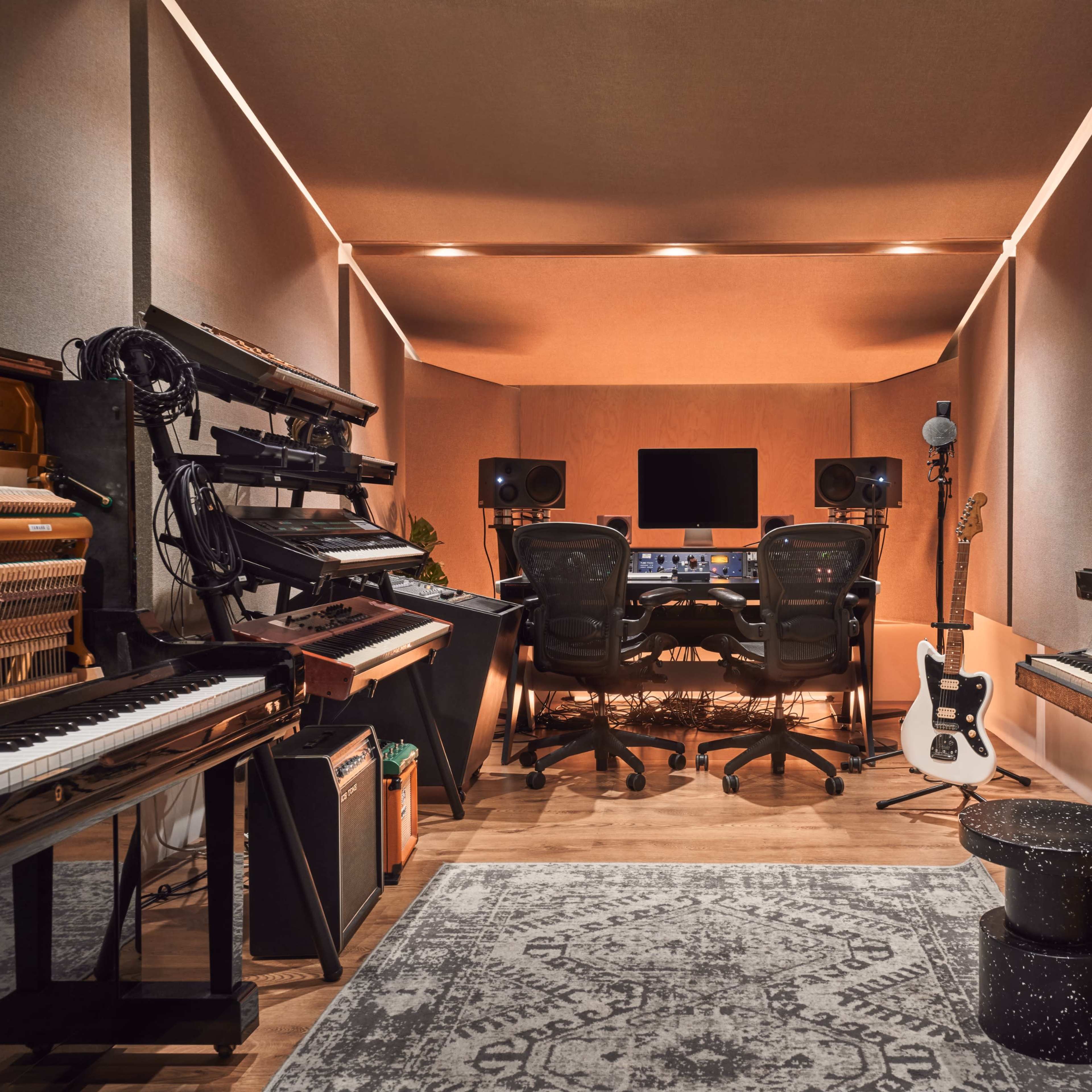 A well-equipped music studio features various instruments, including pianos and keyboards, and is designed with soundproof walls and a central mixing console.