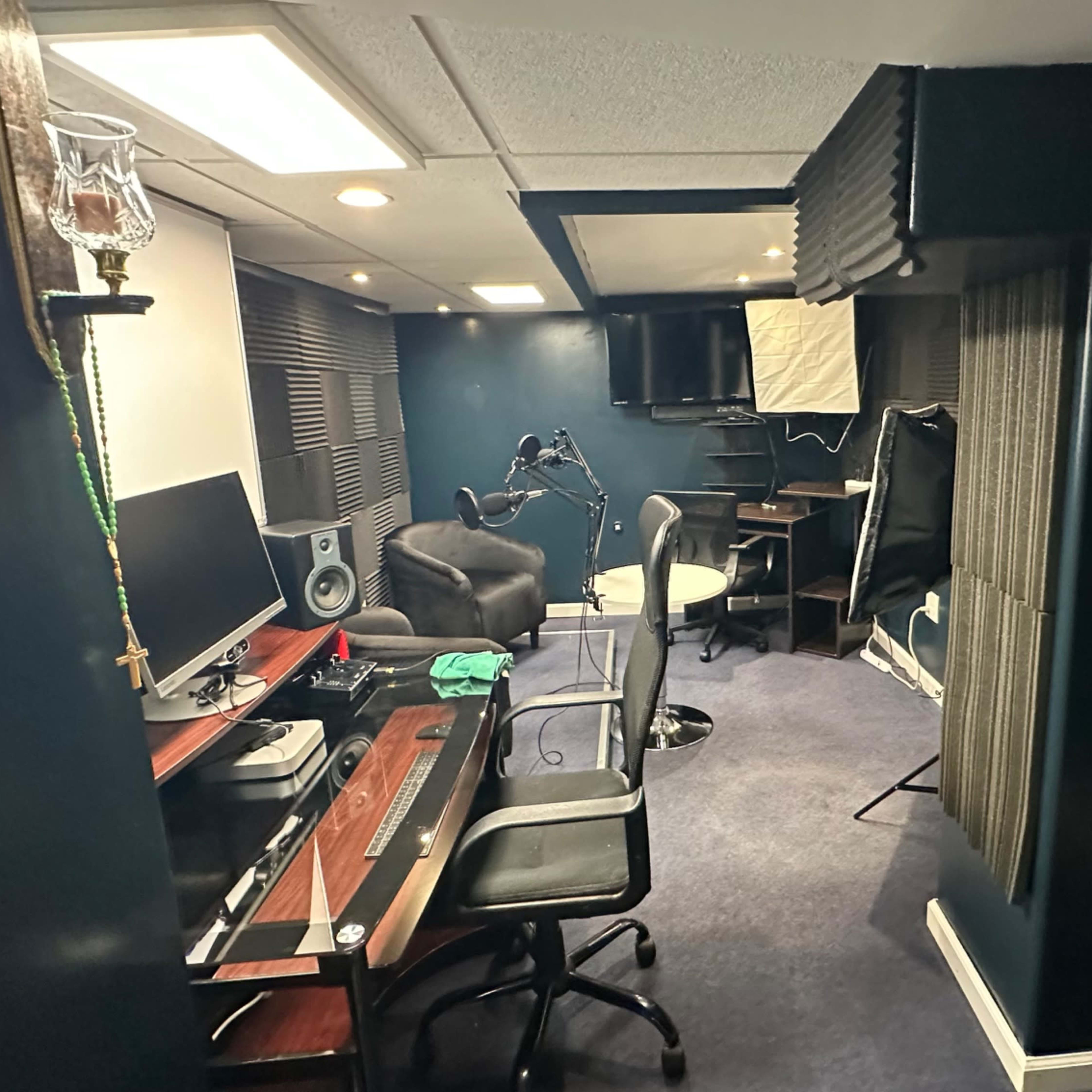A modern home office with a desk, chair, computer setup, and soundproofing panels on the walls.