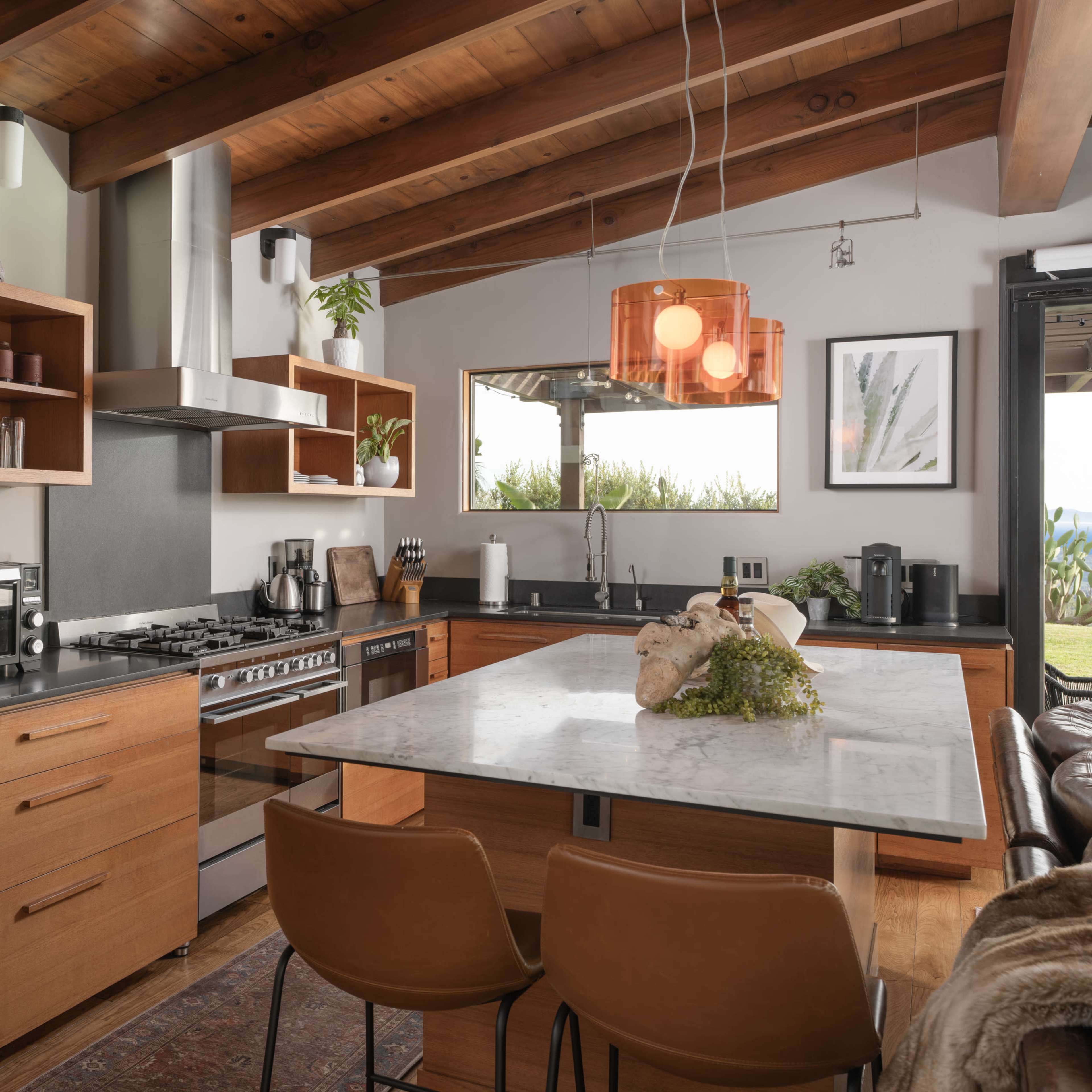 The kitchen features wooden cabinetry, a central marble island with seating, and modern appliances.