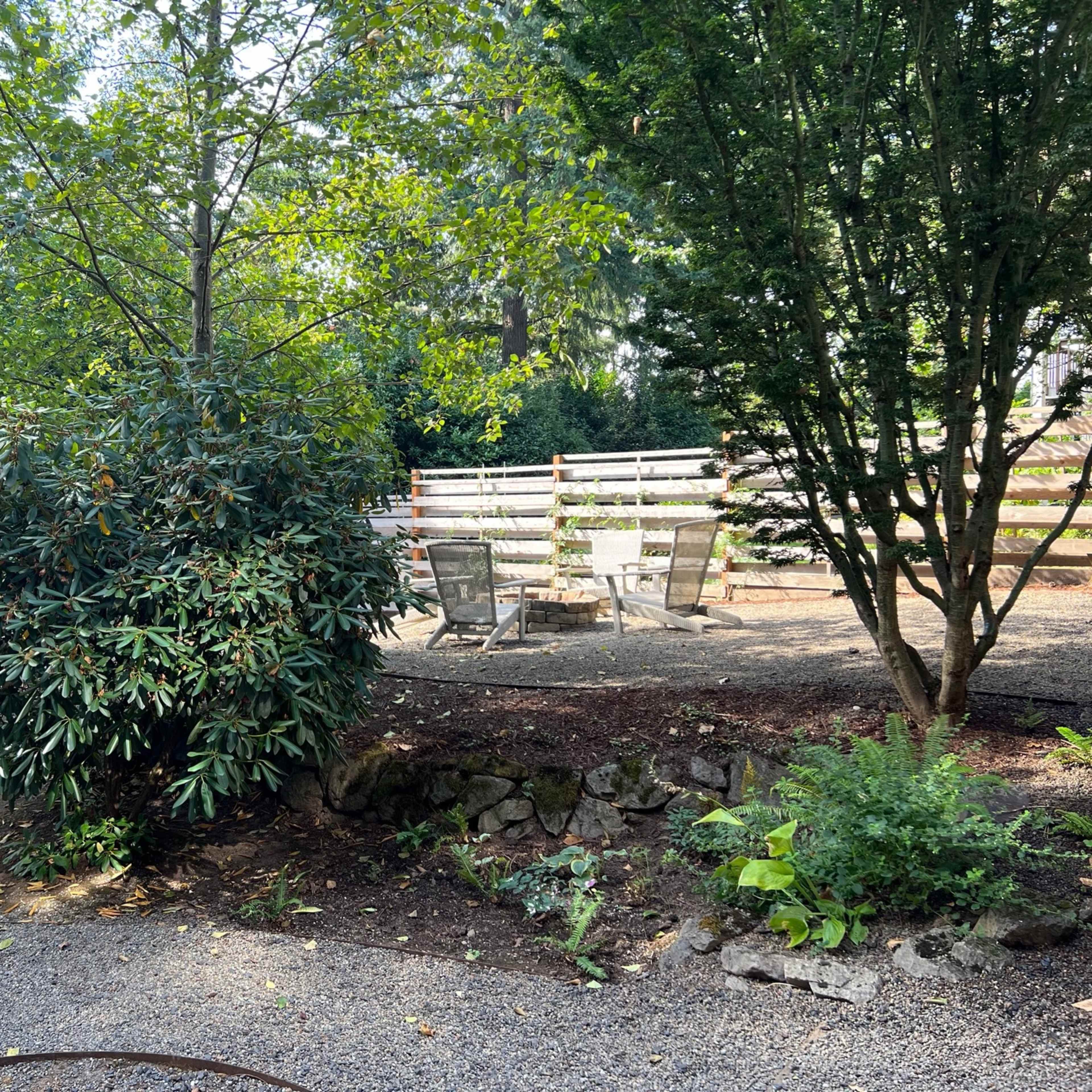 A landscaped outdoor area with seating surrounded by trees and gravel paths.