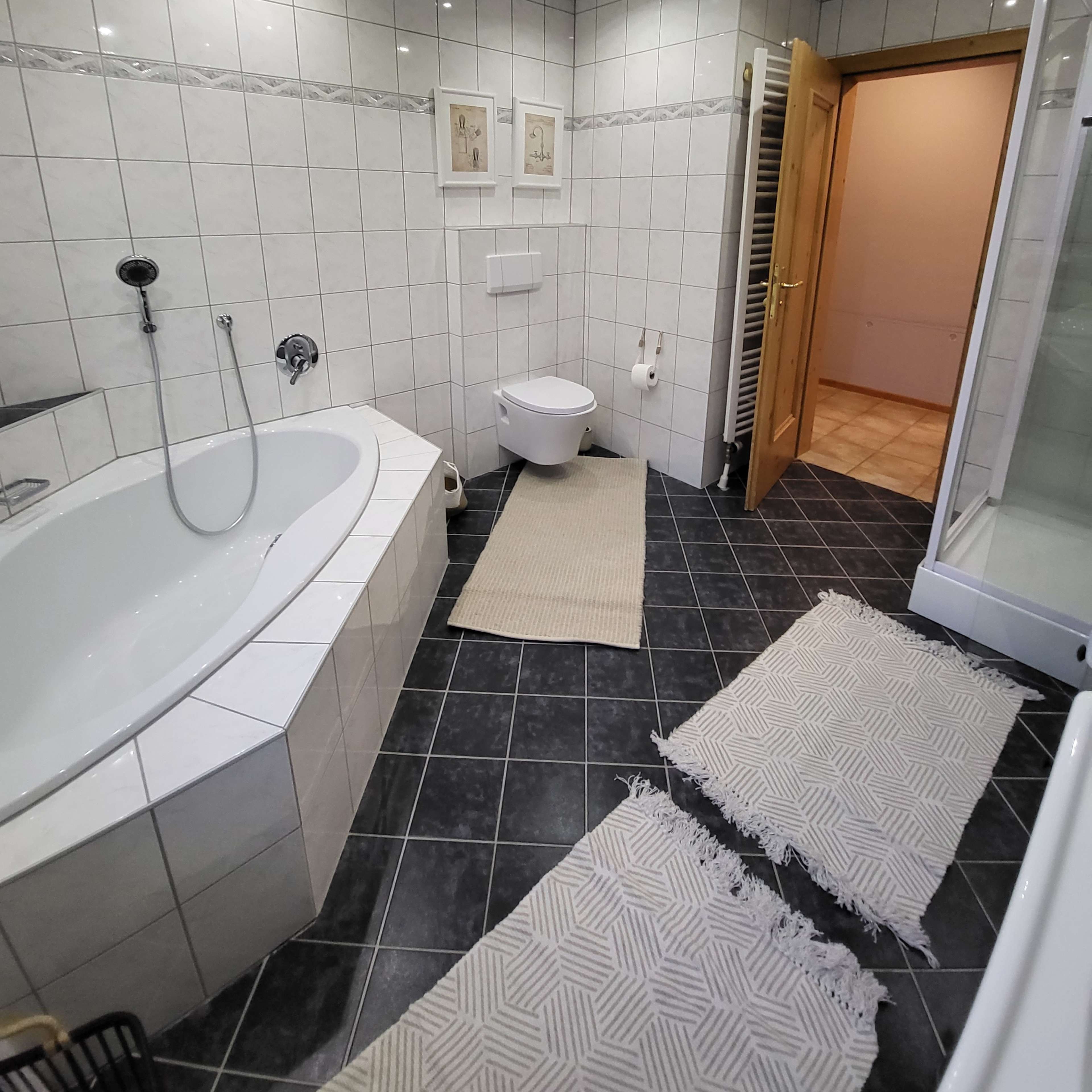 A tiled bathroom with a bathtub, toilet, and a glass-enclosed shower.