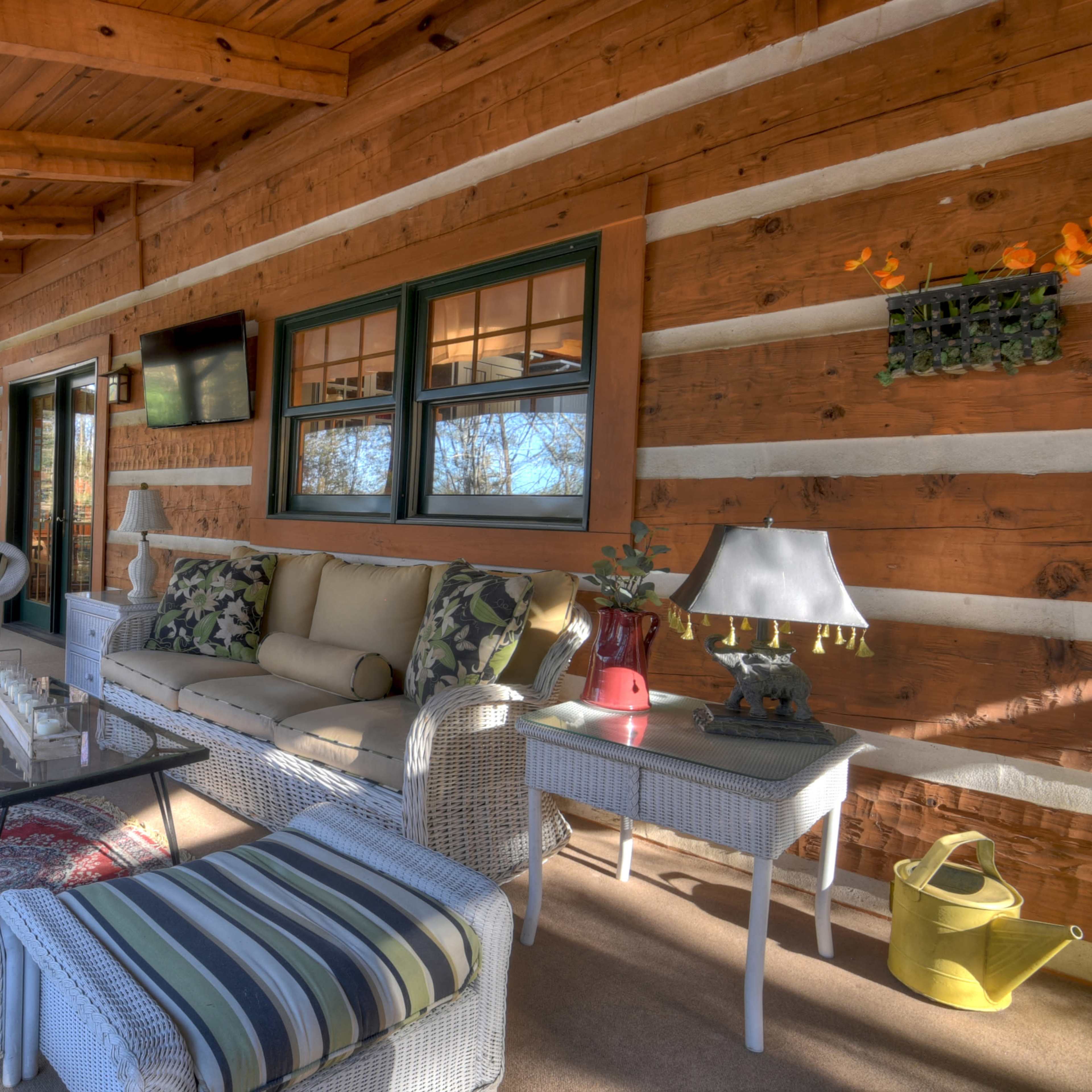 A rustic porch decorated with wooden panels, featuring comfortable seating, a glass coffee table, and various decorative elements.