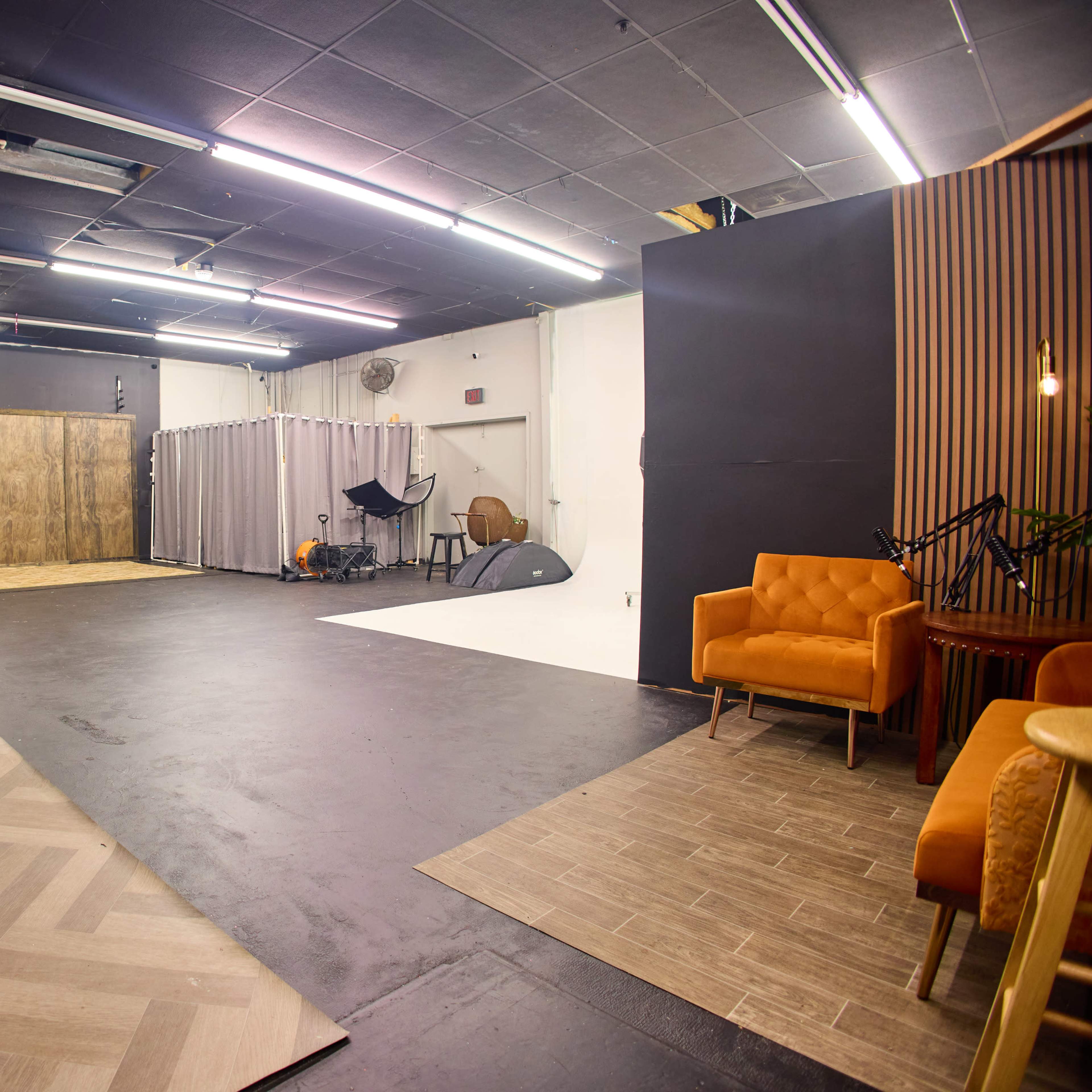 A spacious interior studio with distinct seating areas, a wooden partition, and various photography equipment arranged for a shoot.