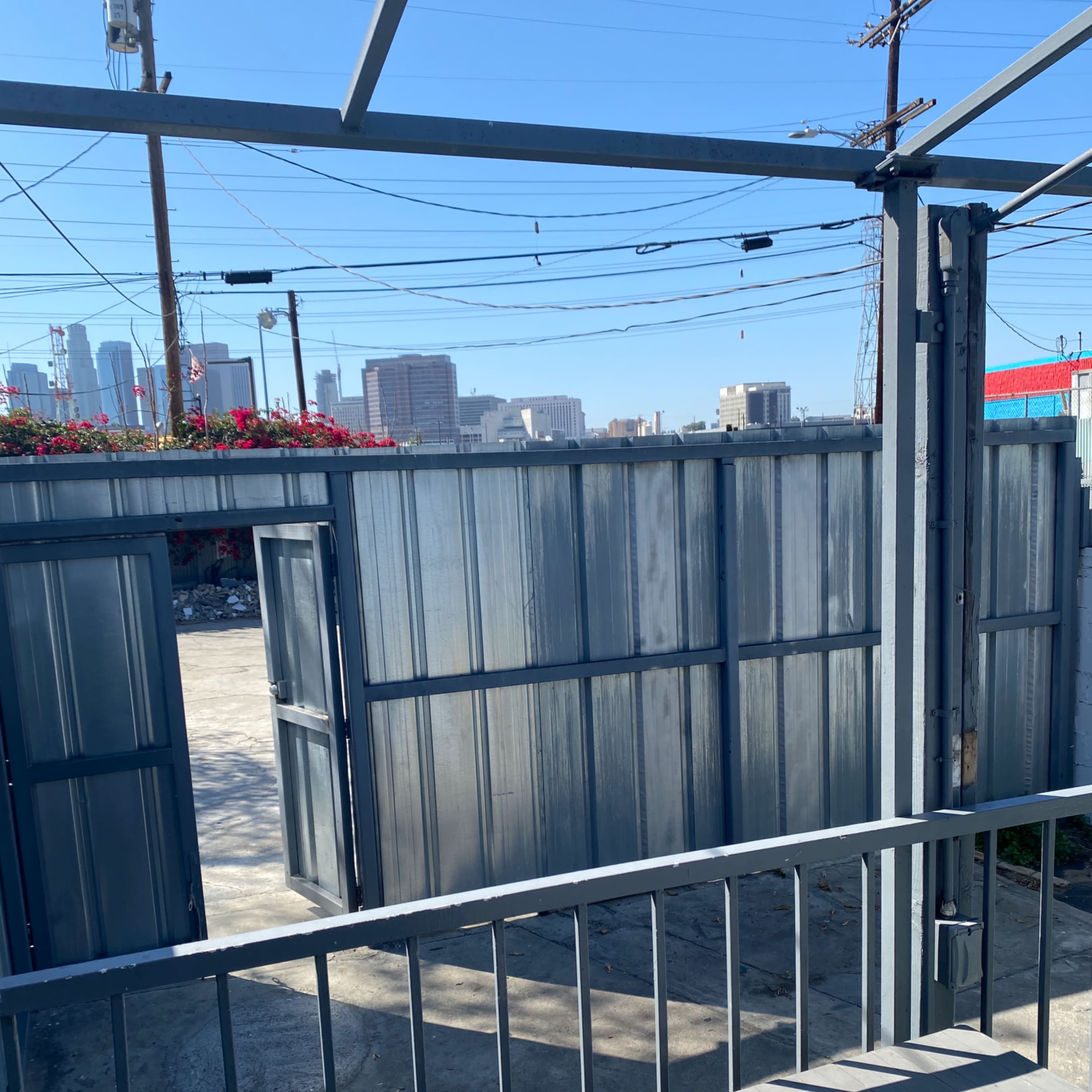 An outdoor view of a fenced area with metal gates and a distant skyline.