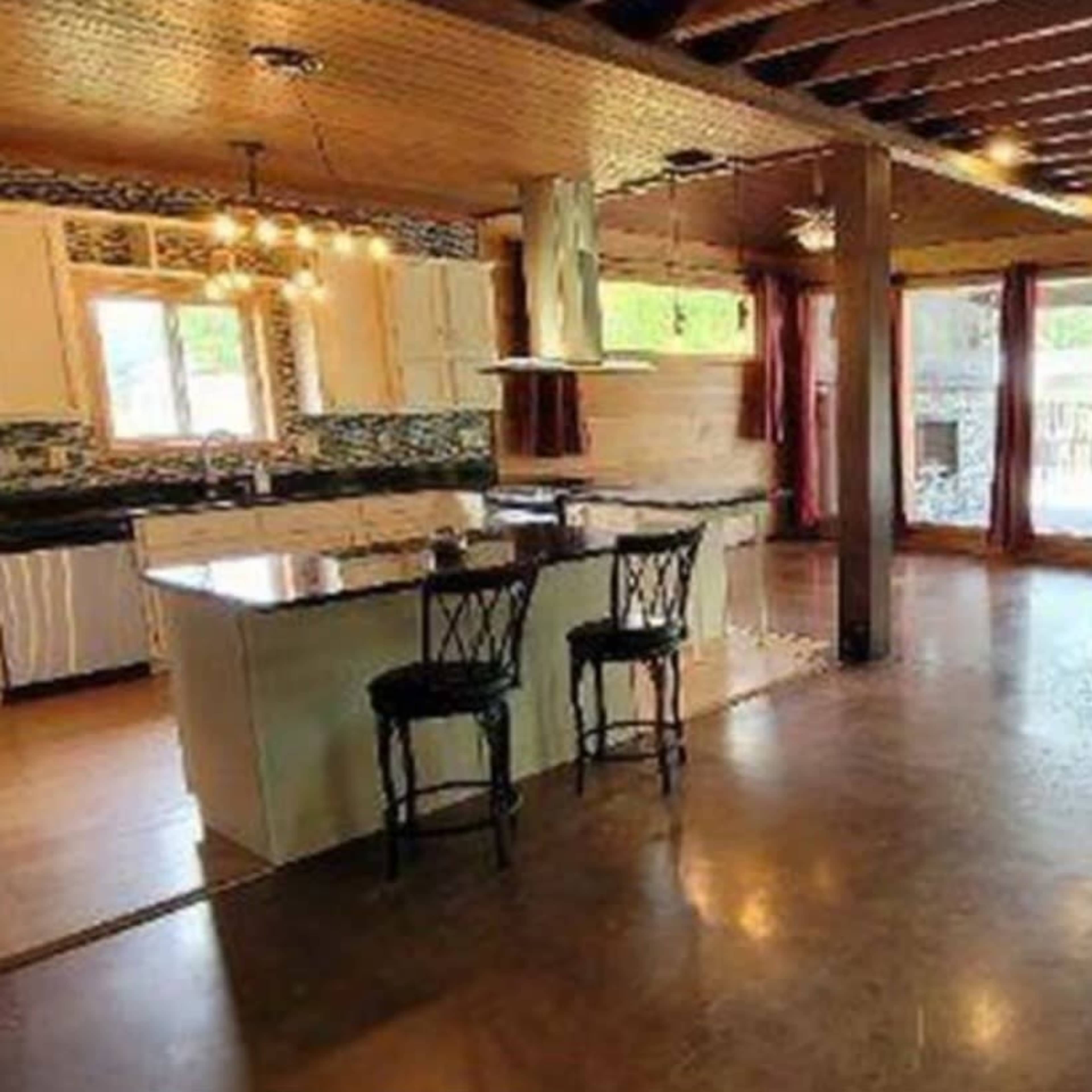 An open-concept living area with a kitchen, dining space, and large windows overlooking a pool.