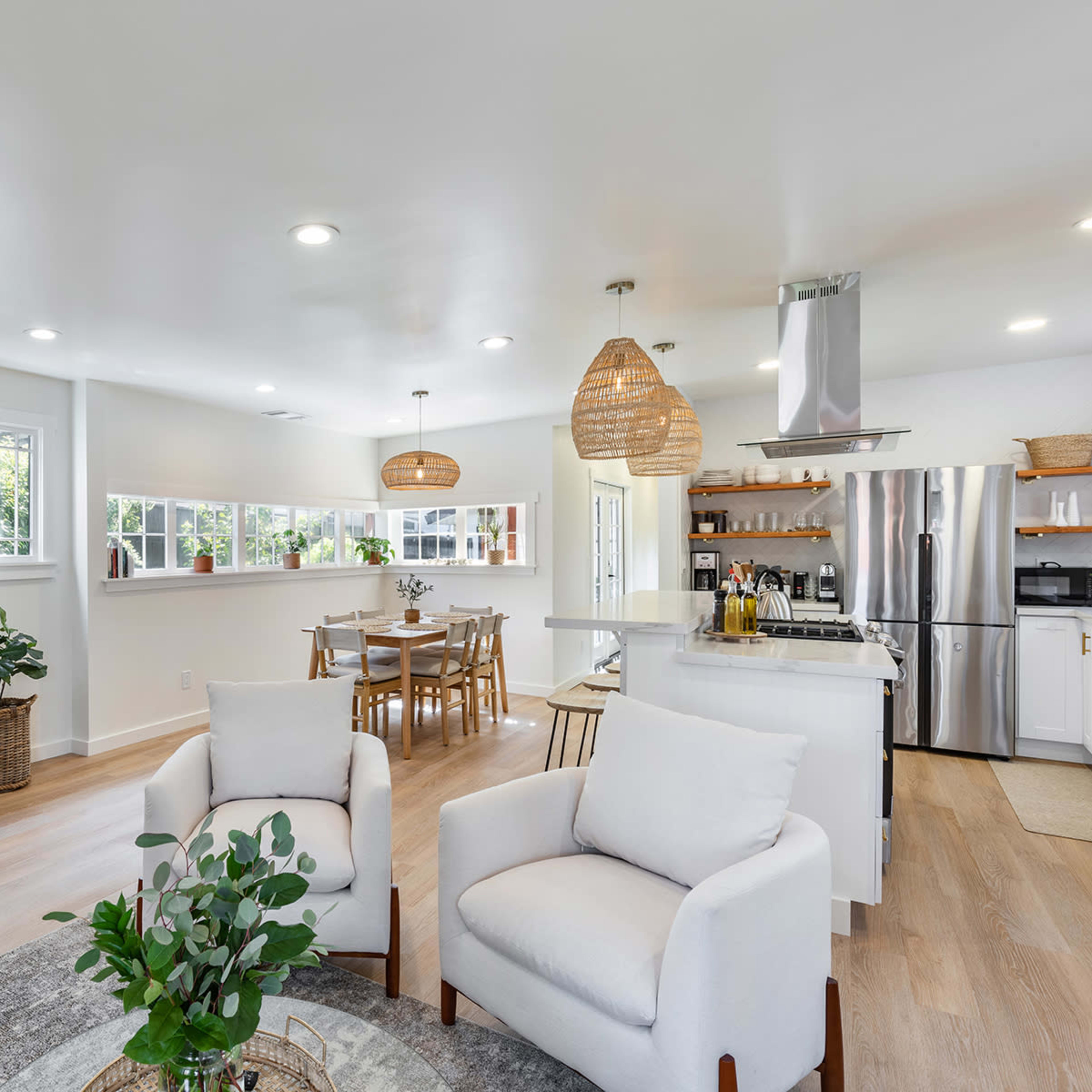 A modern living area features a fireplace, a wall-mounted TV, a dining table, and an open kitchen with island seating.