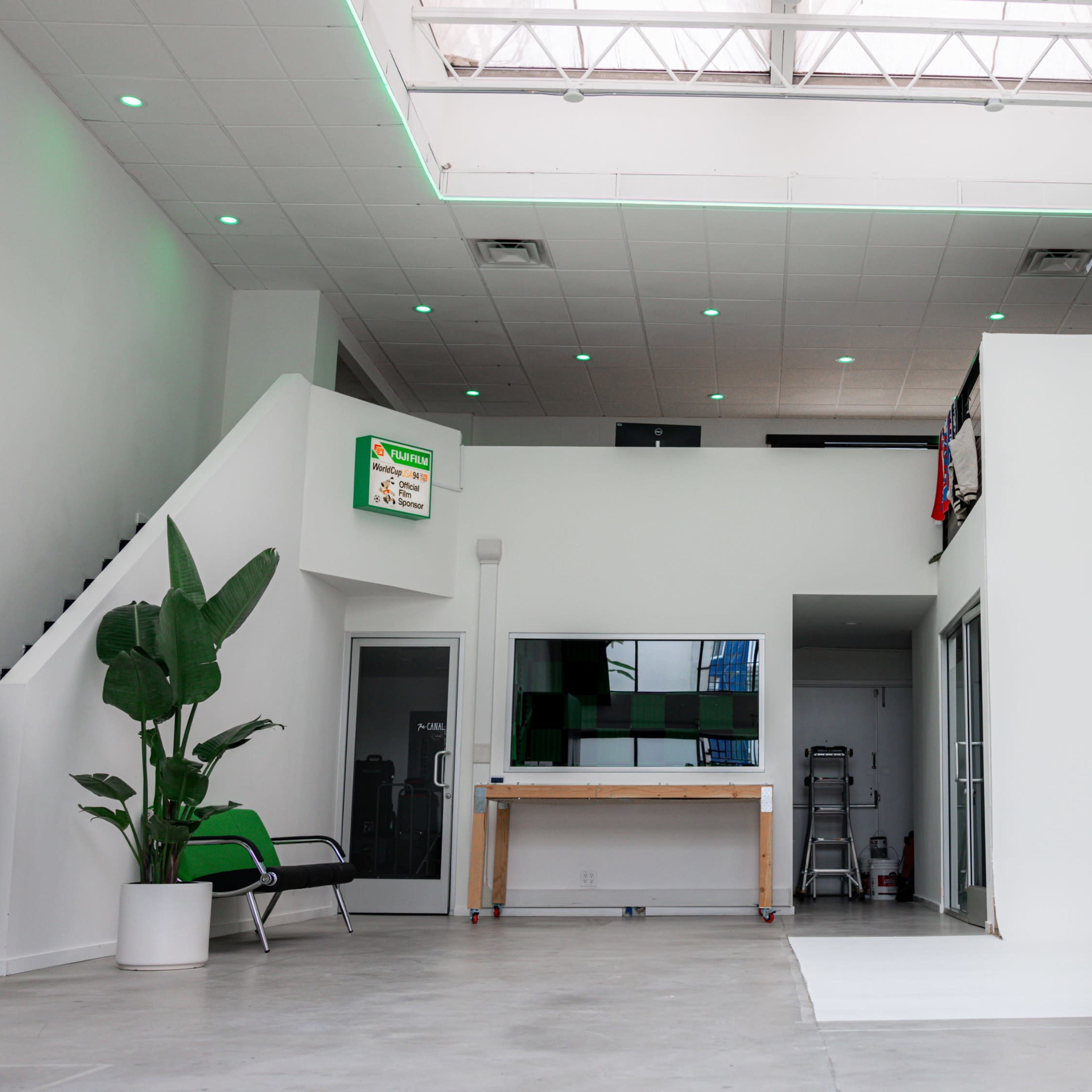 A spacious, modern interior with a large skylight, orange couch, and a staircase leading to an upper level.