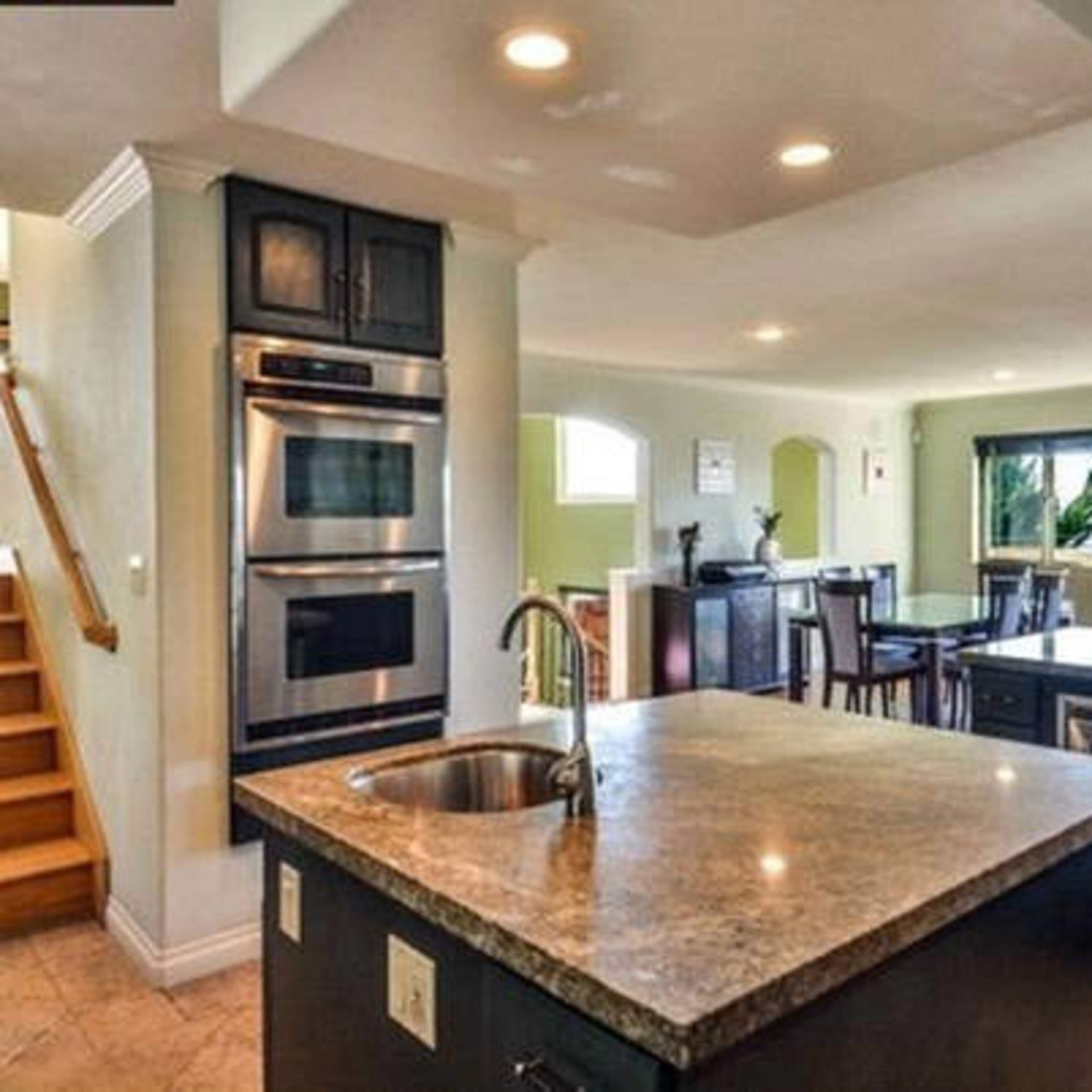 A modern kitchen with a central island and access to a staircase leading to a second level.