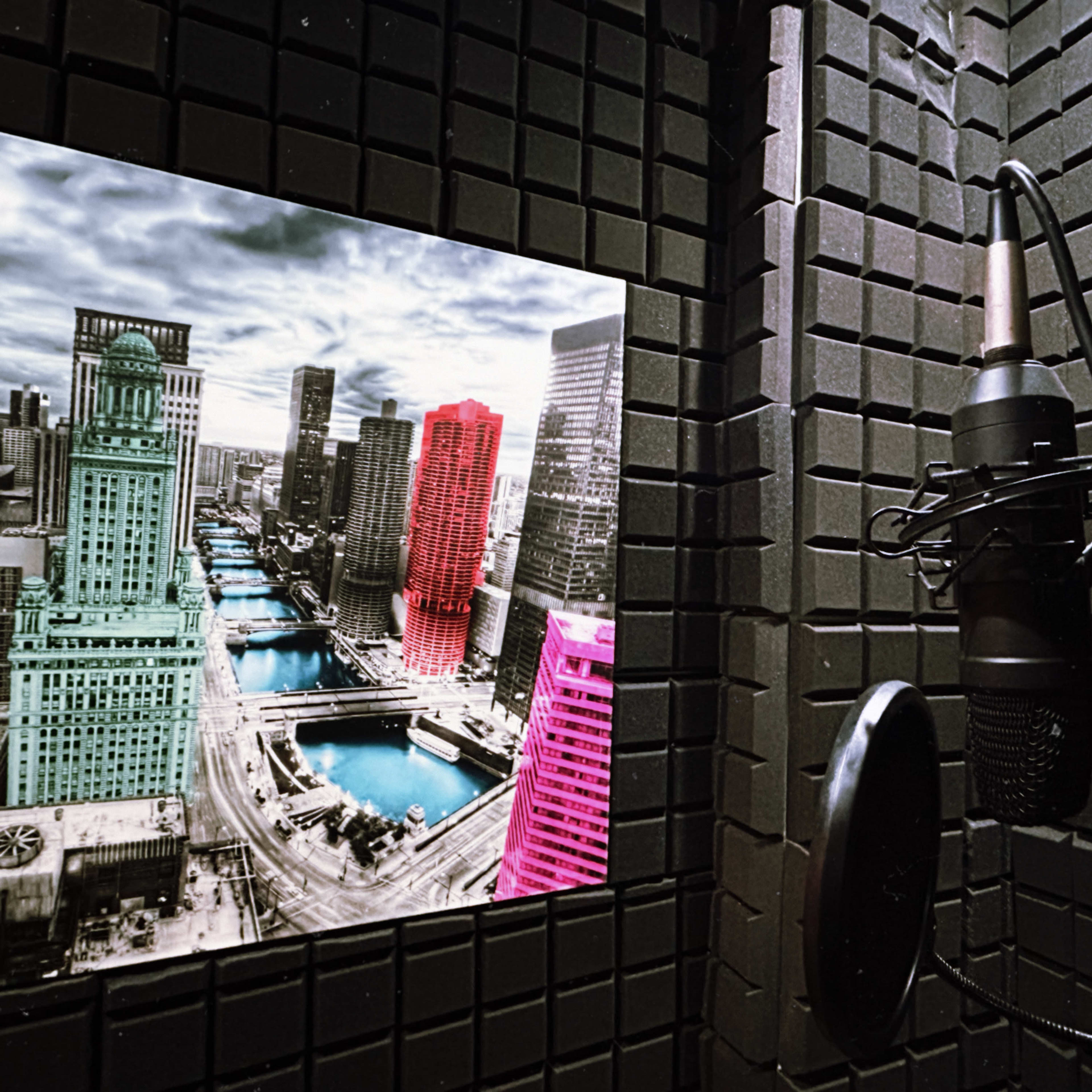 A recording studio booth with a microphone and a large, colorful urban landscape photo on the wall.