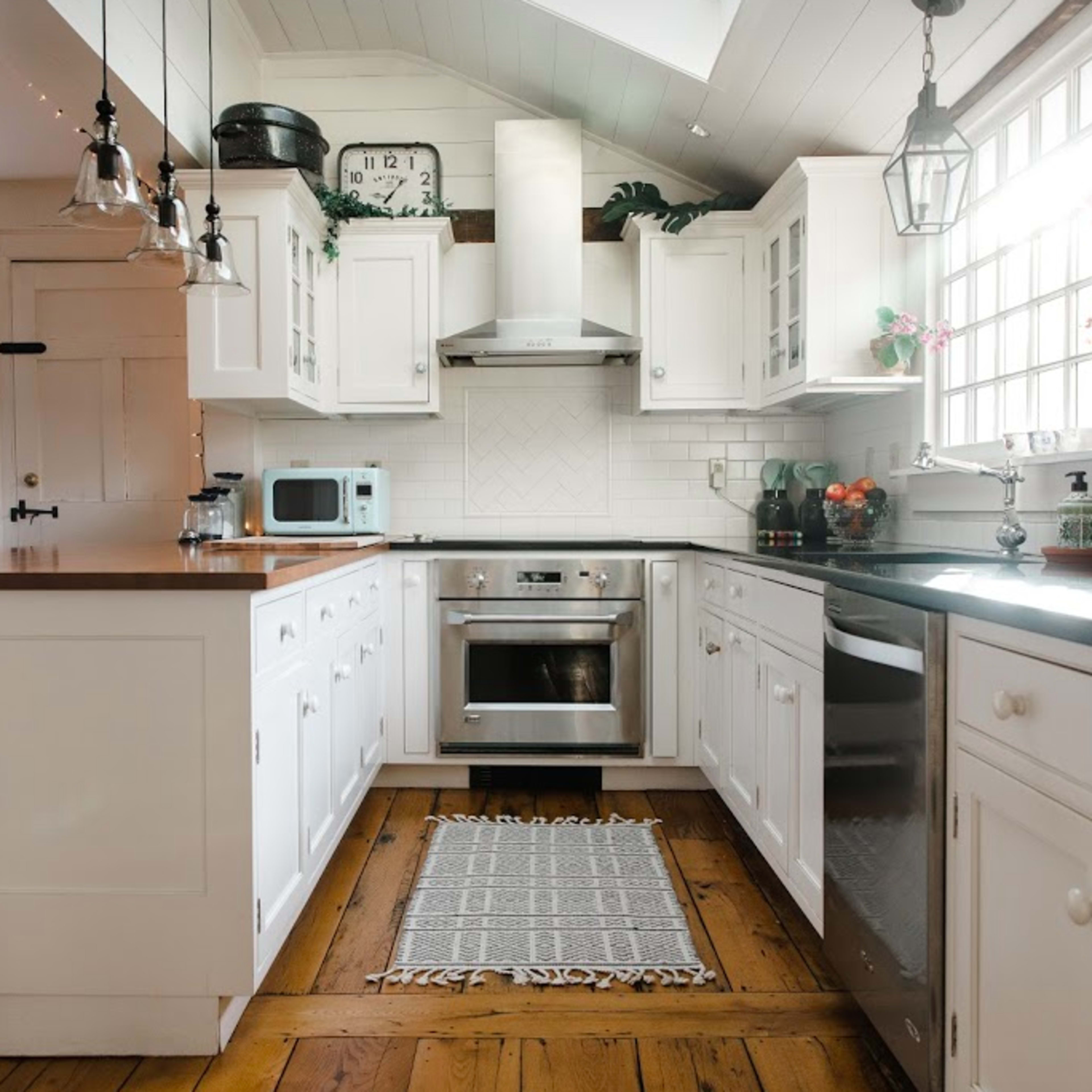 A bright kitchen features white cabinetry, a central island with a wooden countertop, and stainless steel appliances.