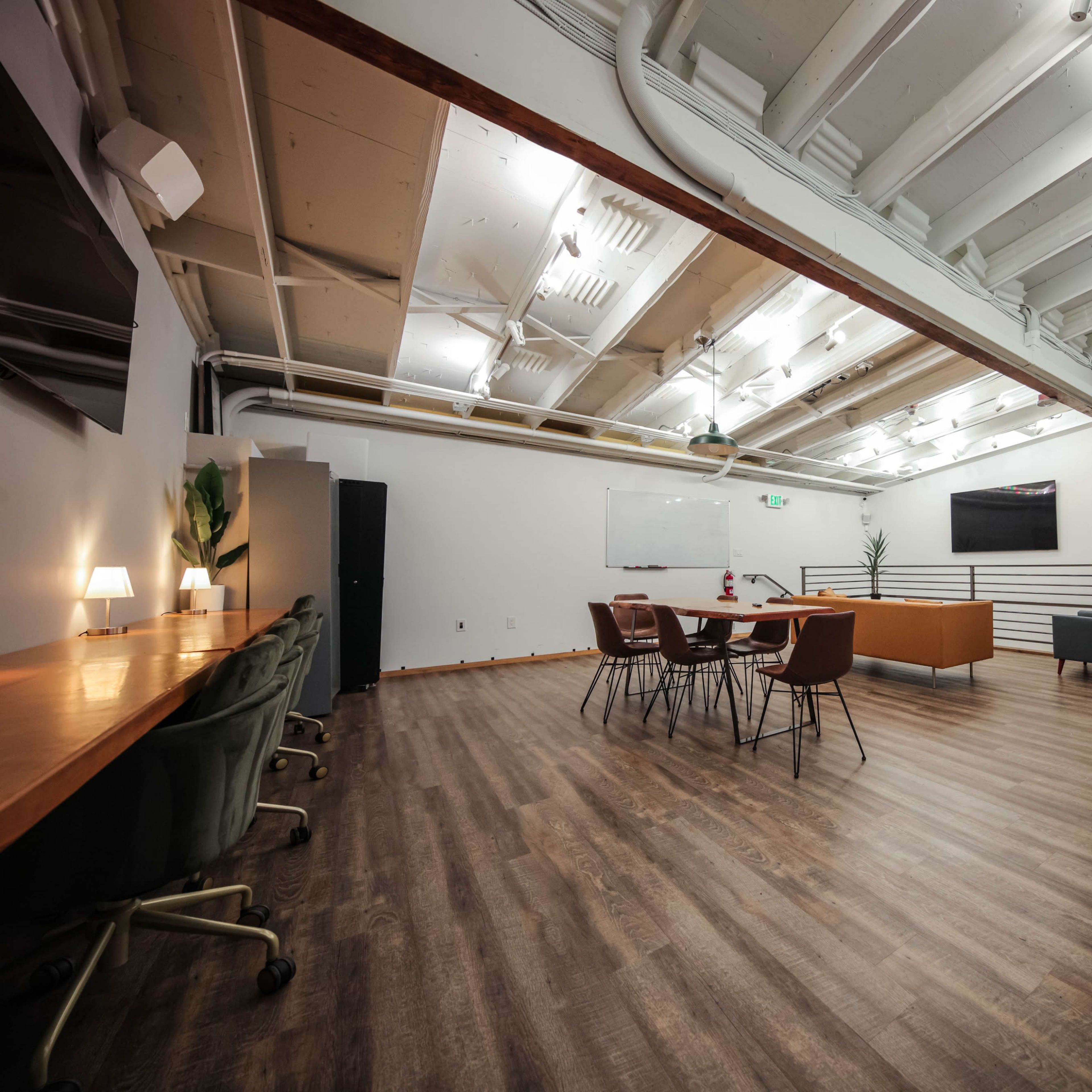 A spacious office interior with a meeting area, individual workstations, and modern furniture under a high ceiling.