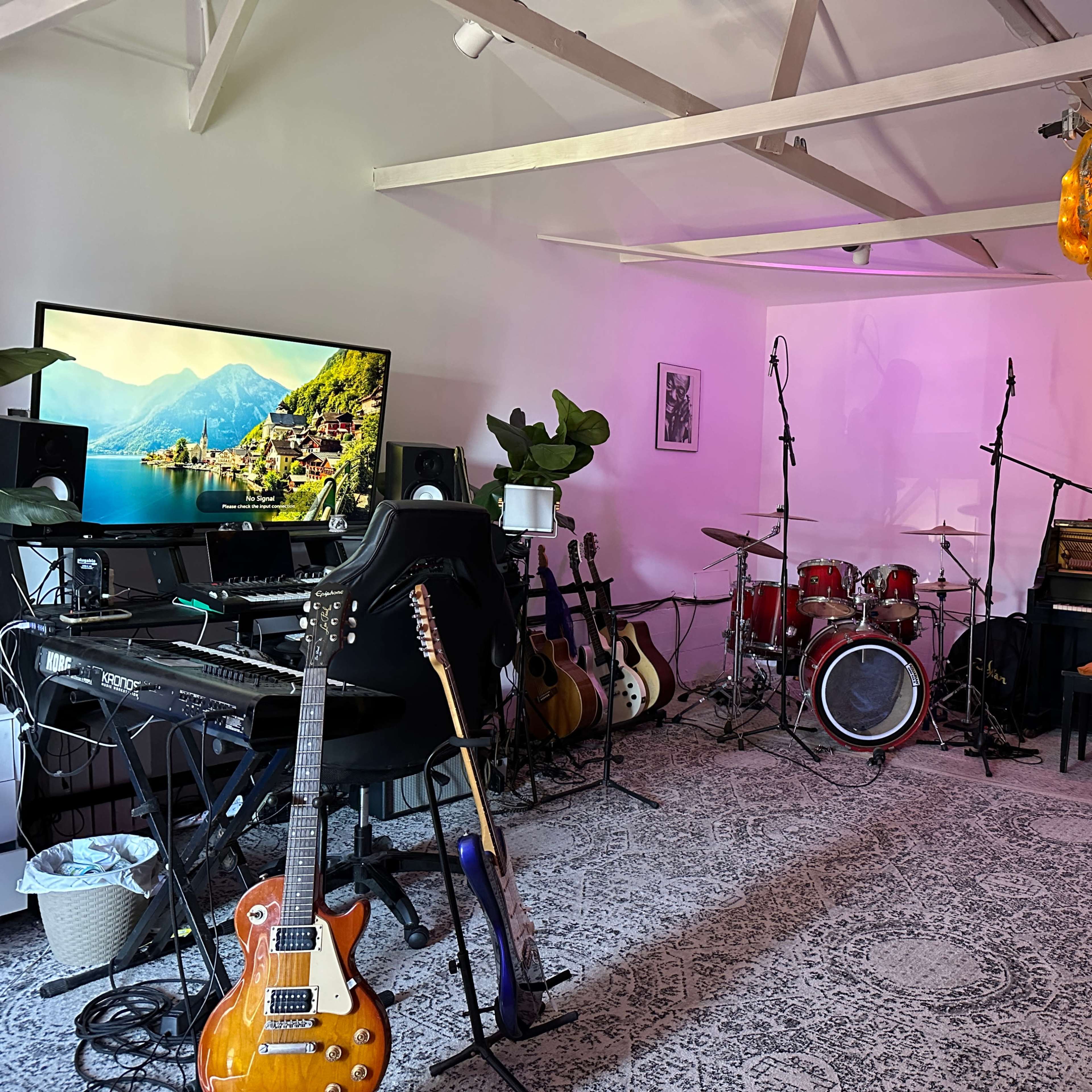 A music studio is equipped with various instruments, including guitars, a keyboard, a drum set, and a grand piano, alongside a large television and artistic decor.