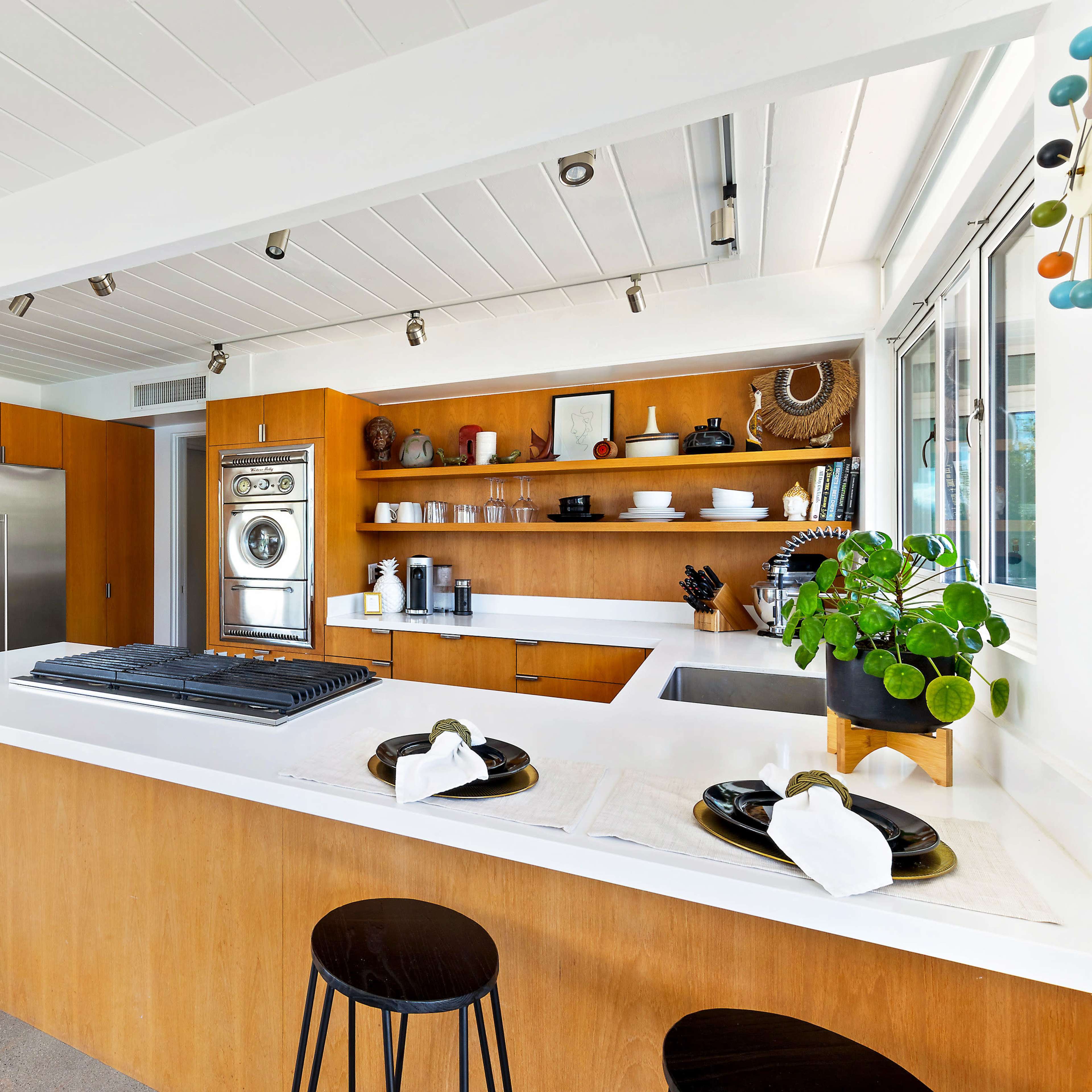 A modern kitchen featuring wooden cabinetry, stainless steel appliances, and a central island with a cooktop.