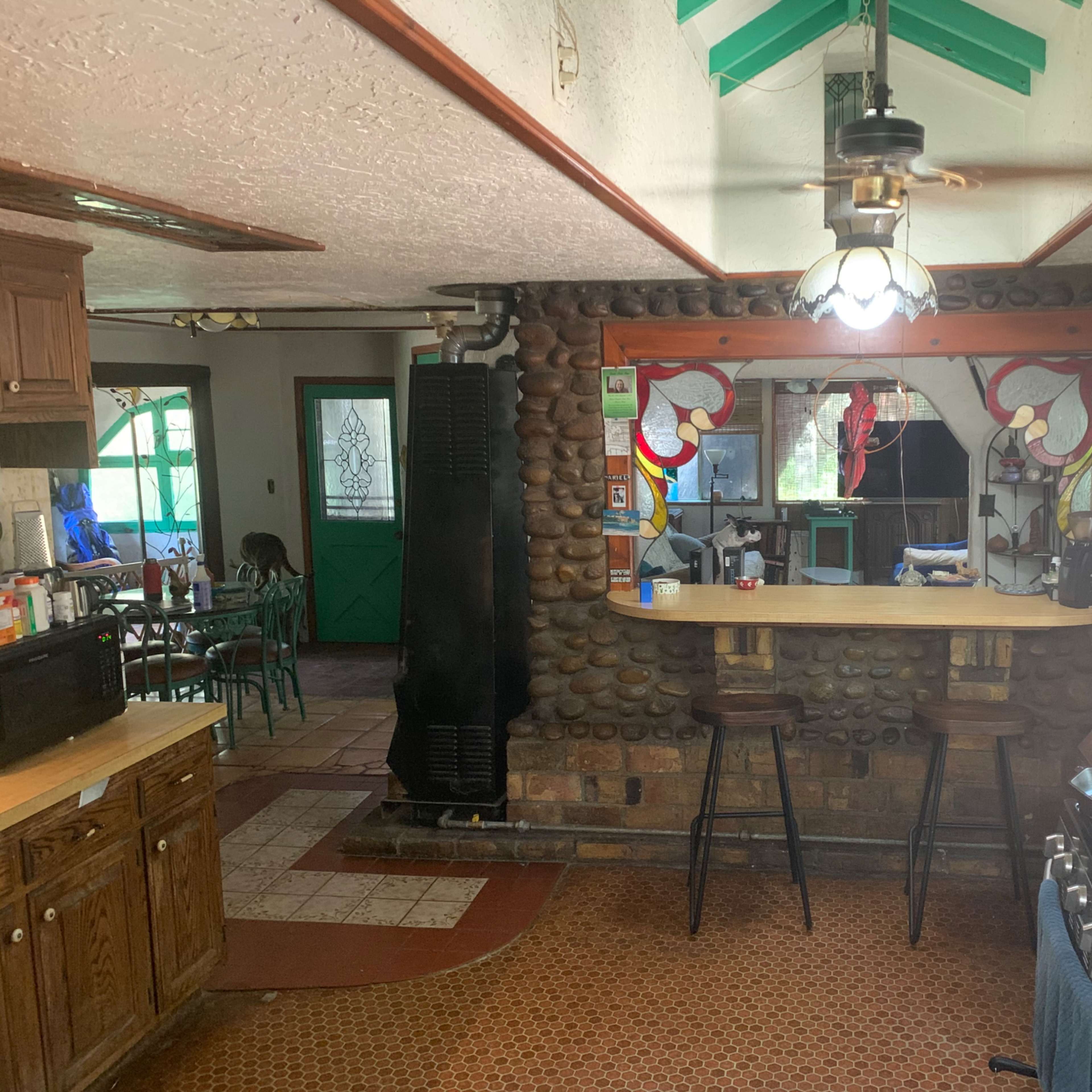 A rustic kitchen with stone walls, a breakfast bar, and various appliances, including a stove and refrigerator.