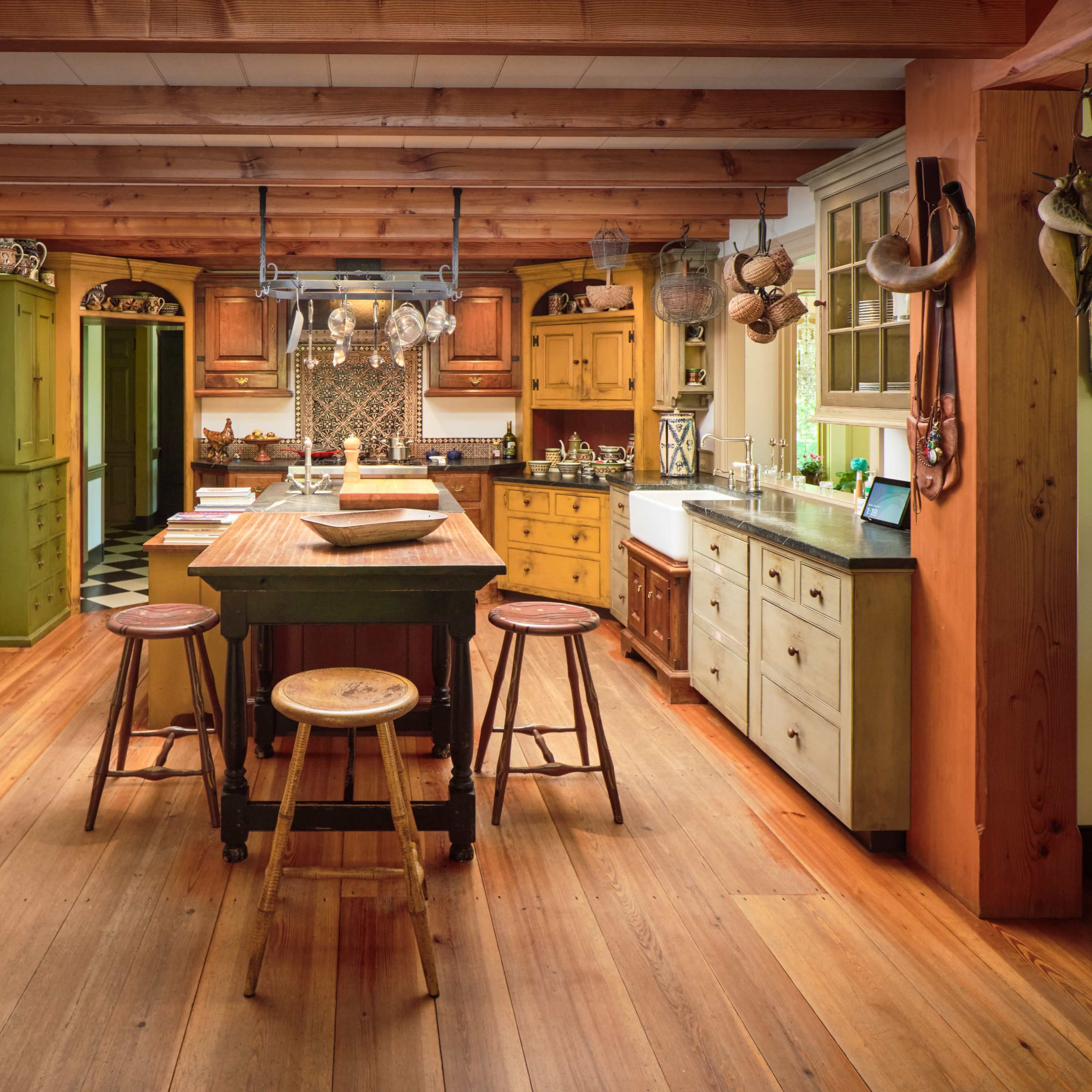 A spacious kitchen featuring a central island with stools, wooden cabinets, and a variety of kitchen accessories.