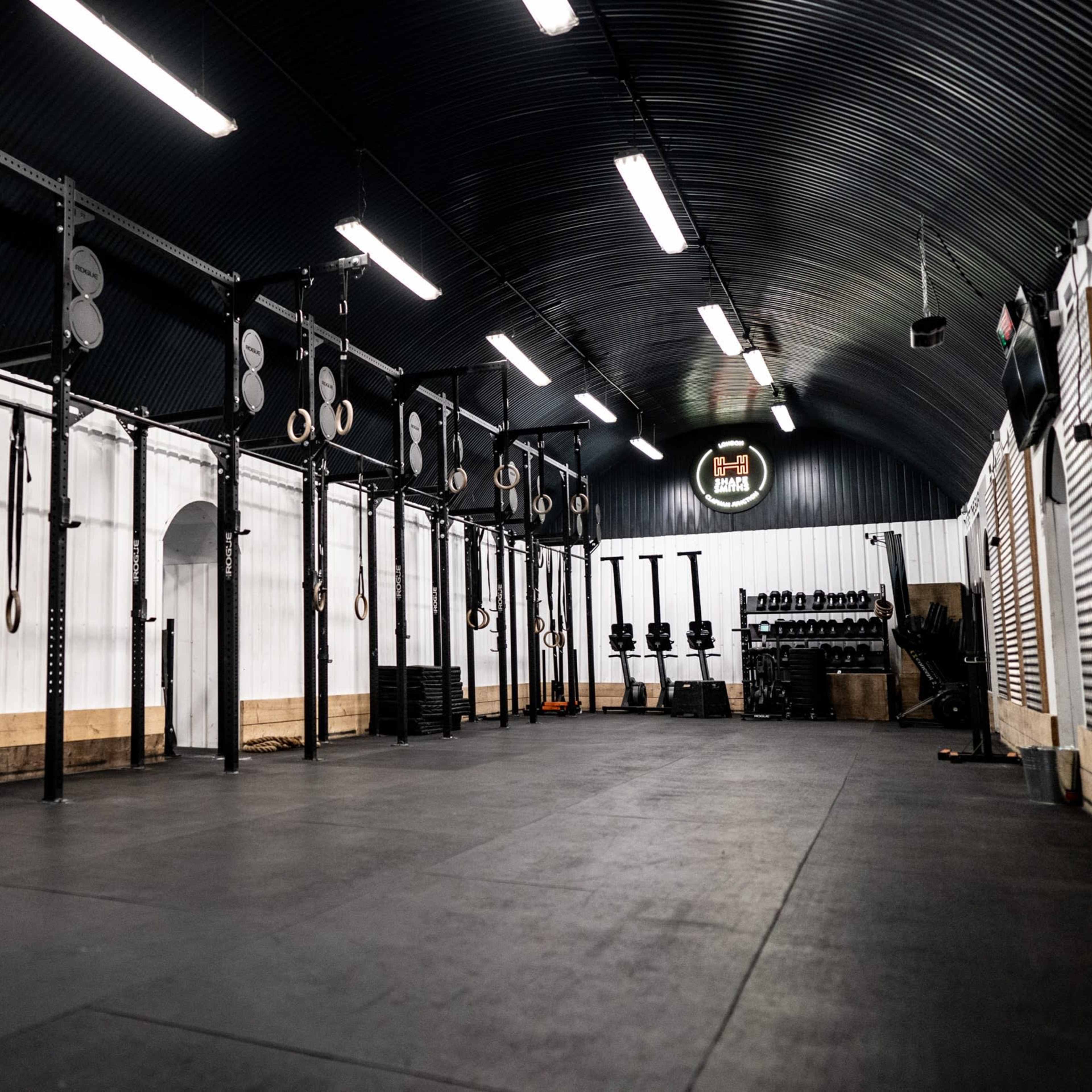 An indoor gym space equipped with exercise equipment, including pull-up bars, weightlifting racks, and fitness machines.