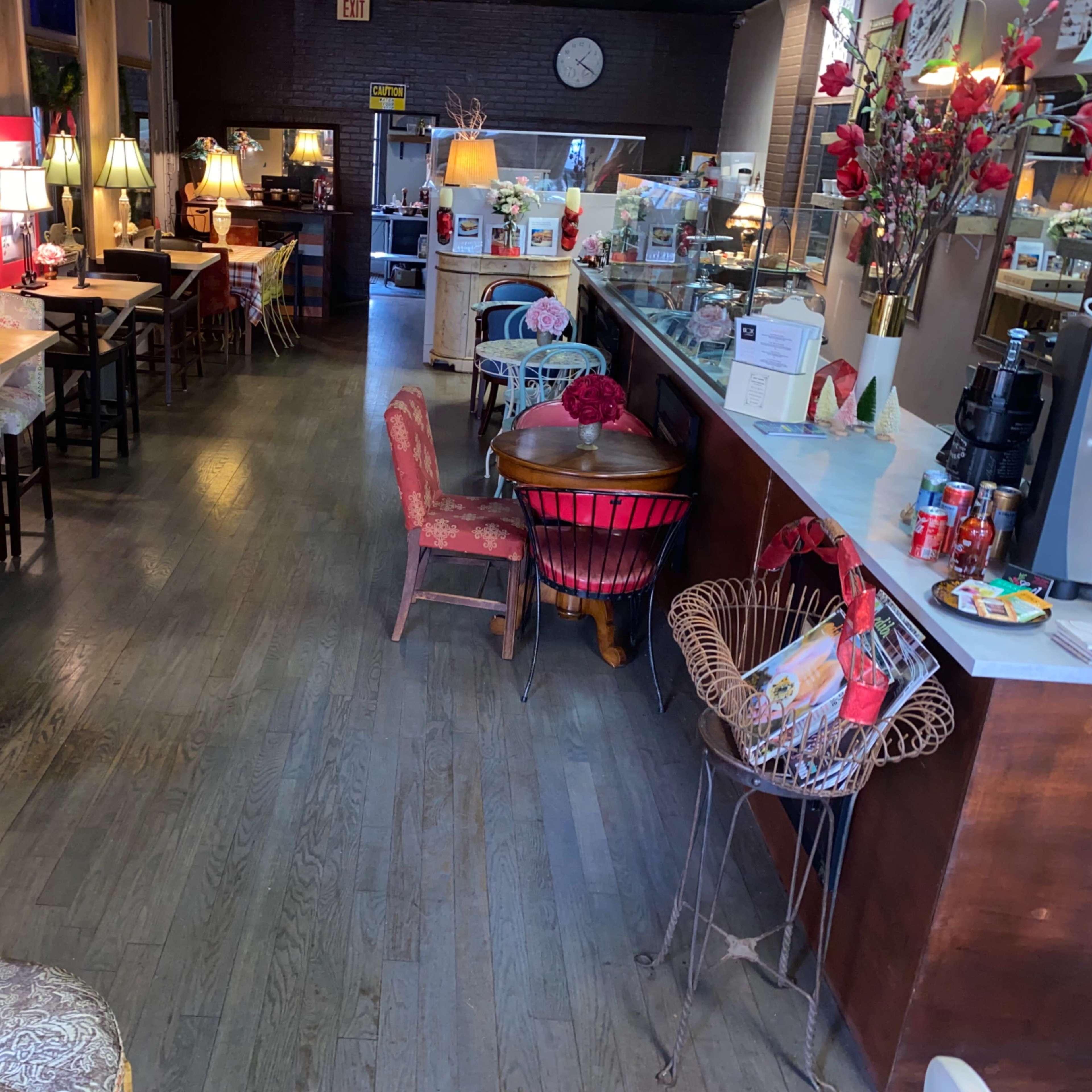 A cozy café interior with wooden floors, various seating arrangements, and decorative lamps.