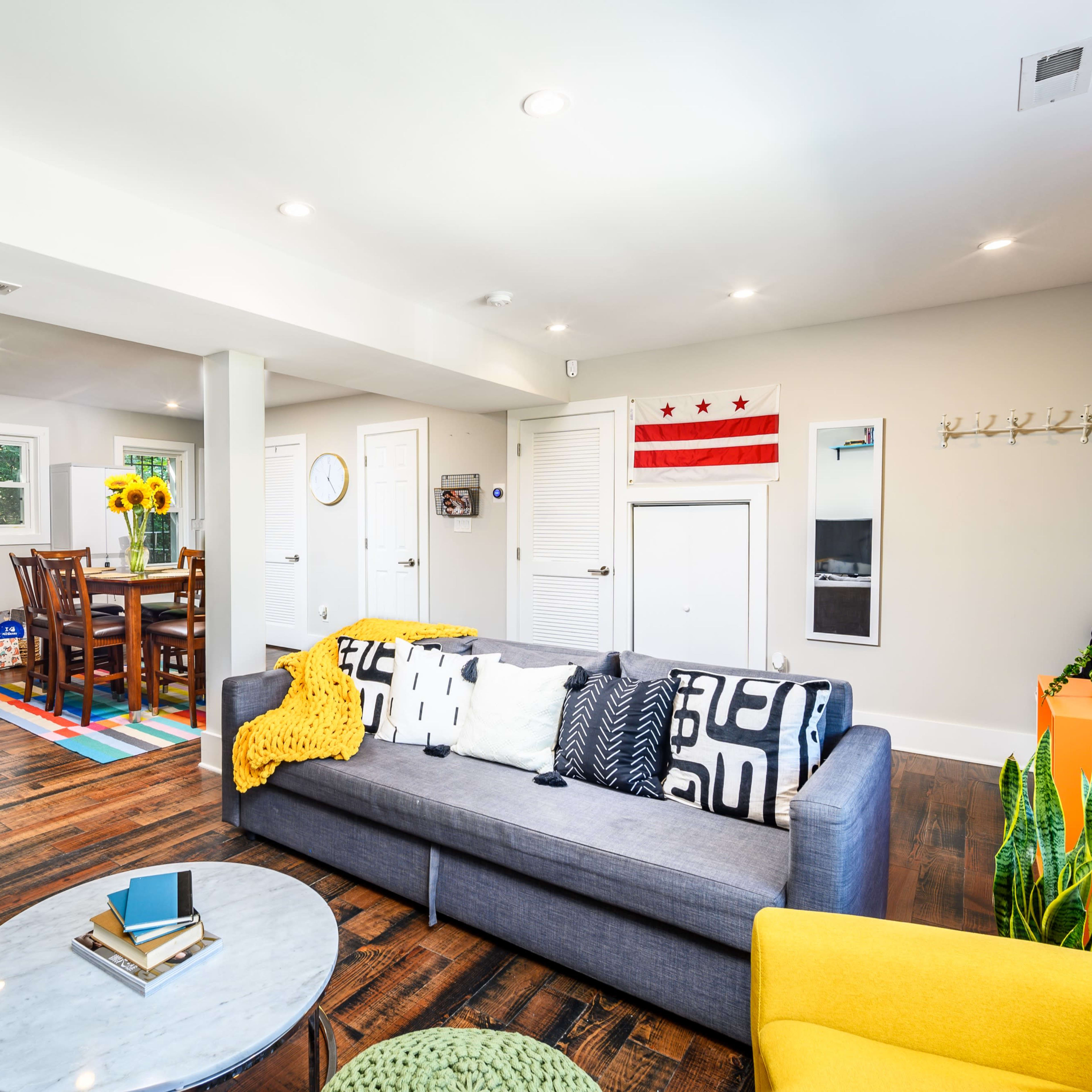 A bright and modern open-concept living area featuring a sofa, coffee table, and dining space with a table surrounded by chairs.
