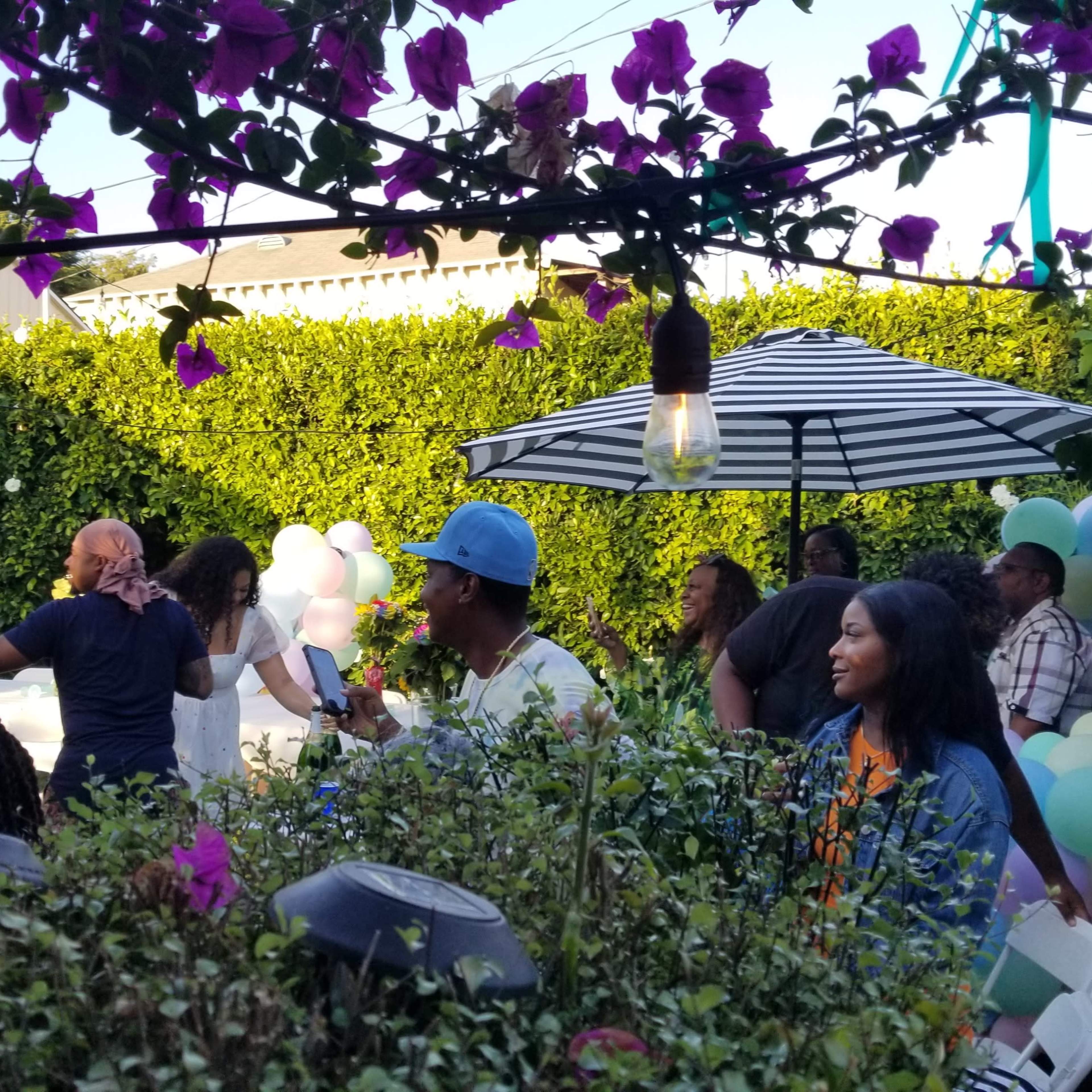 A garden party scene features guests enjoying themselves under a striped umbrella, surrounded by greenery and colorful decorations.